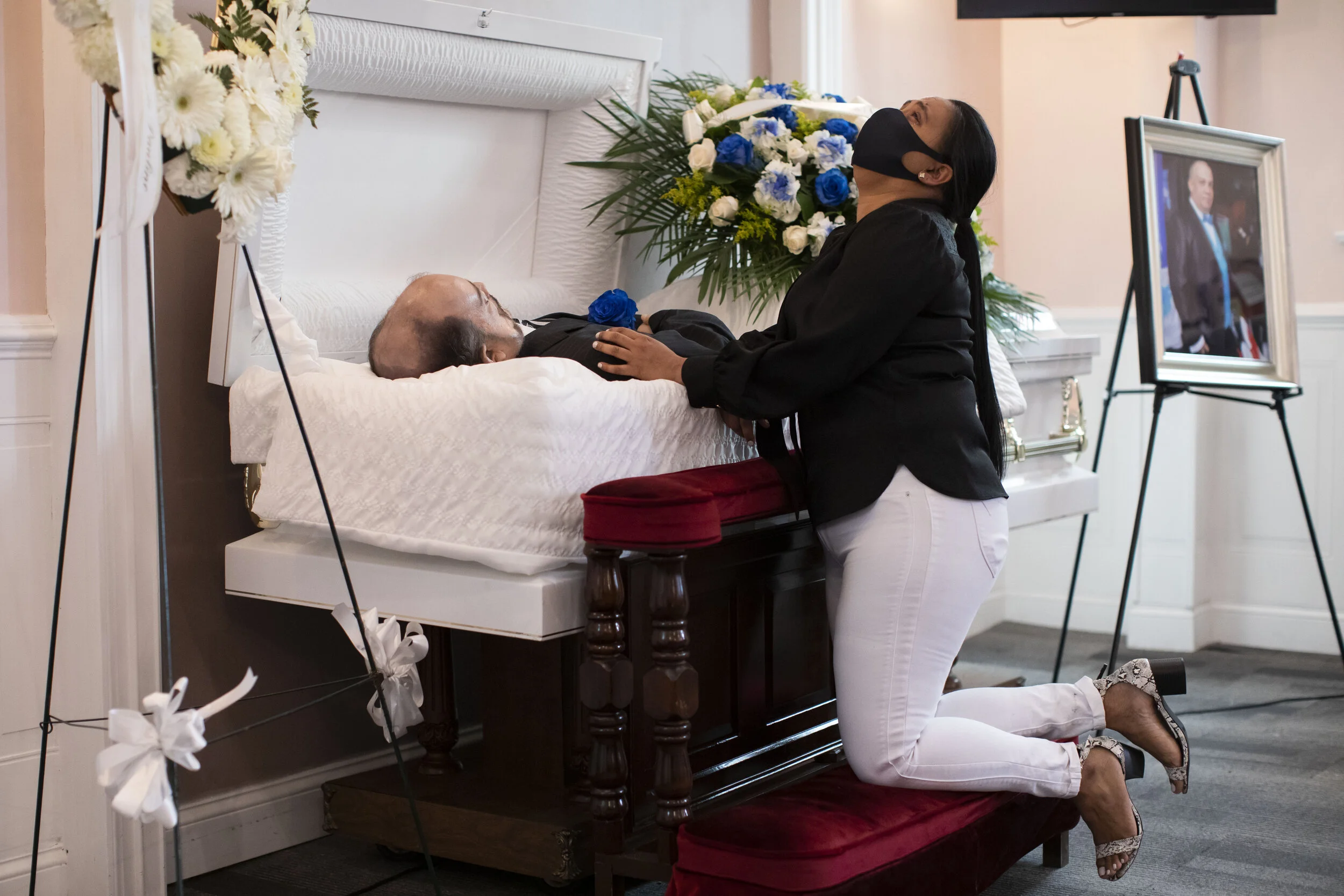  Maria Ortiz kneels next to the body of her partner Jose Holguin, who died due to complications from the coronavirus disease. Mr. Holguin, 50, was a cancer sufferer who contracted COVID-19 while admitted to hospital for other health ailments.  