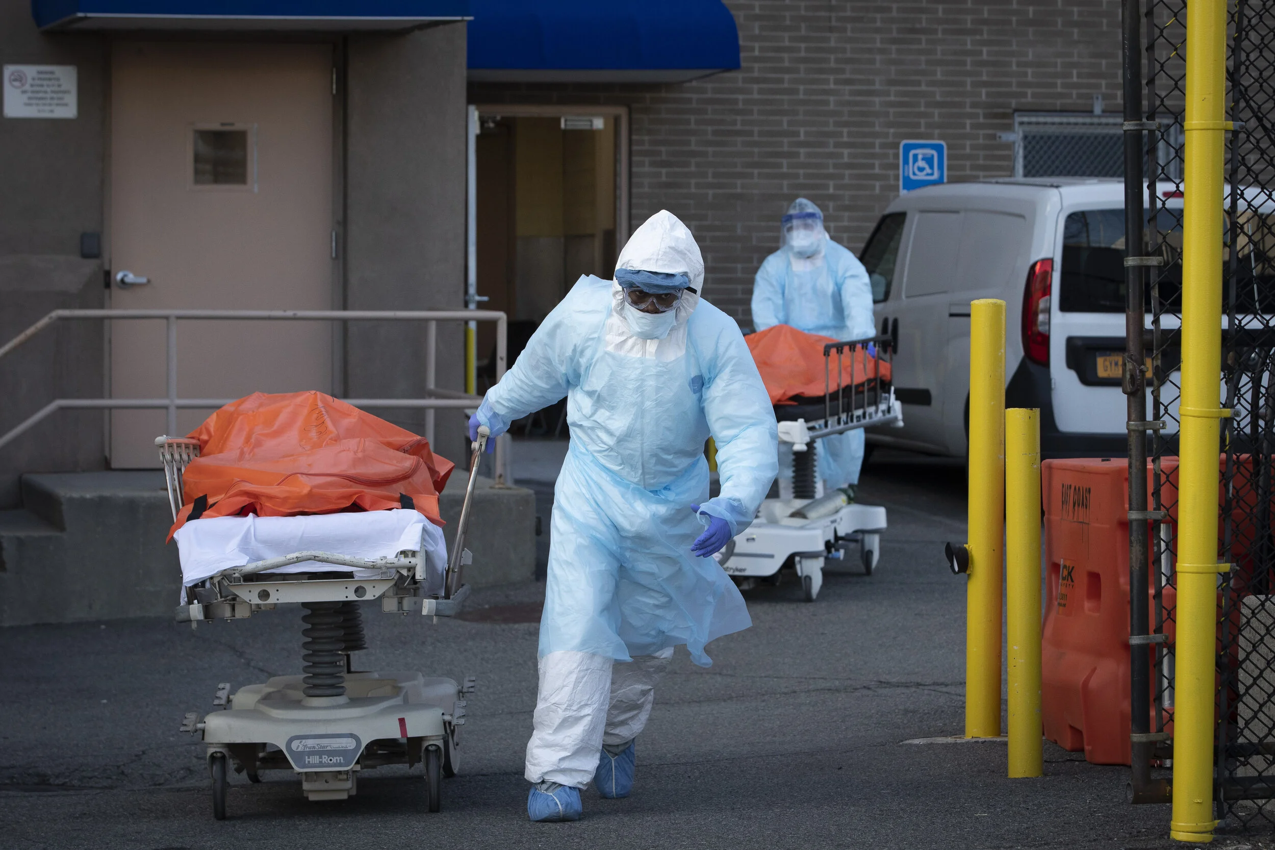  Healthcare workers wheel the bodies of coronavirus victims from a rear door of the Wyckoff Heights Medical Center, Brooklyn, to an awaiting temporary morgue.  As the death rate spiked, a scene like this became common due to overflow of hospital morg