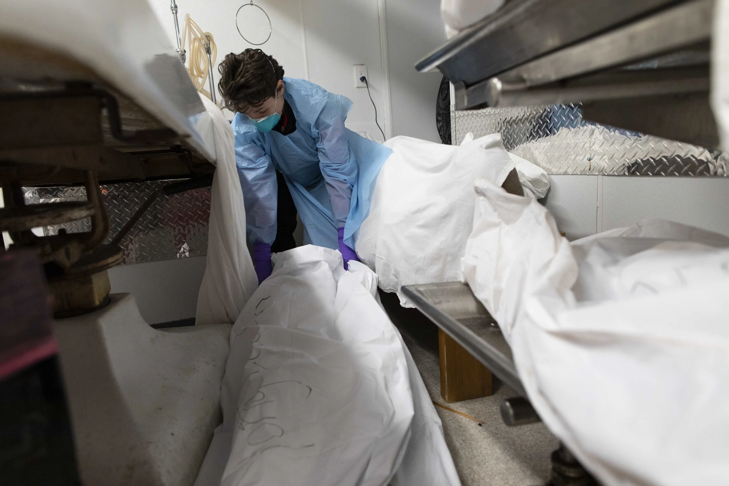  Lily Sage attempts to position a body into a free space in the prep room, where embalmings take place. 
