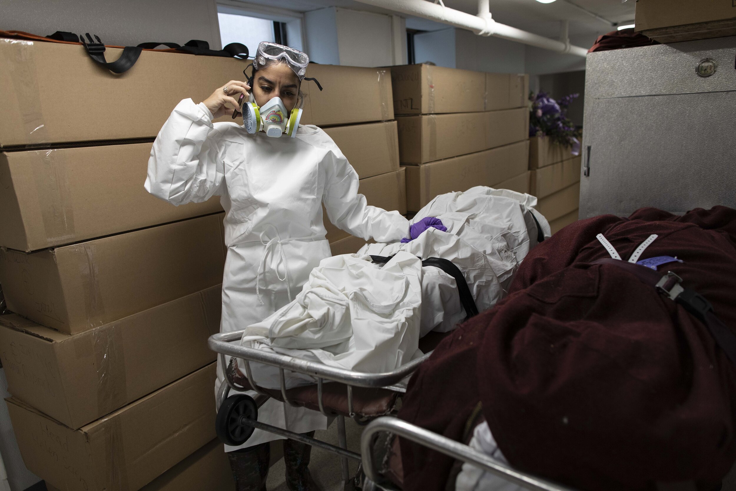  Alisha Narvaez takes a phone call in in front of a bodies stacked in cremation boxes. The cremation boxes are a cost effective way to handle cremations, avoiding the expense of a casket.  