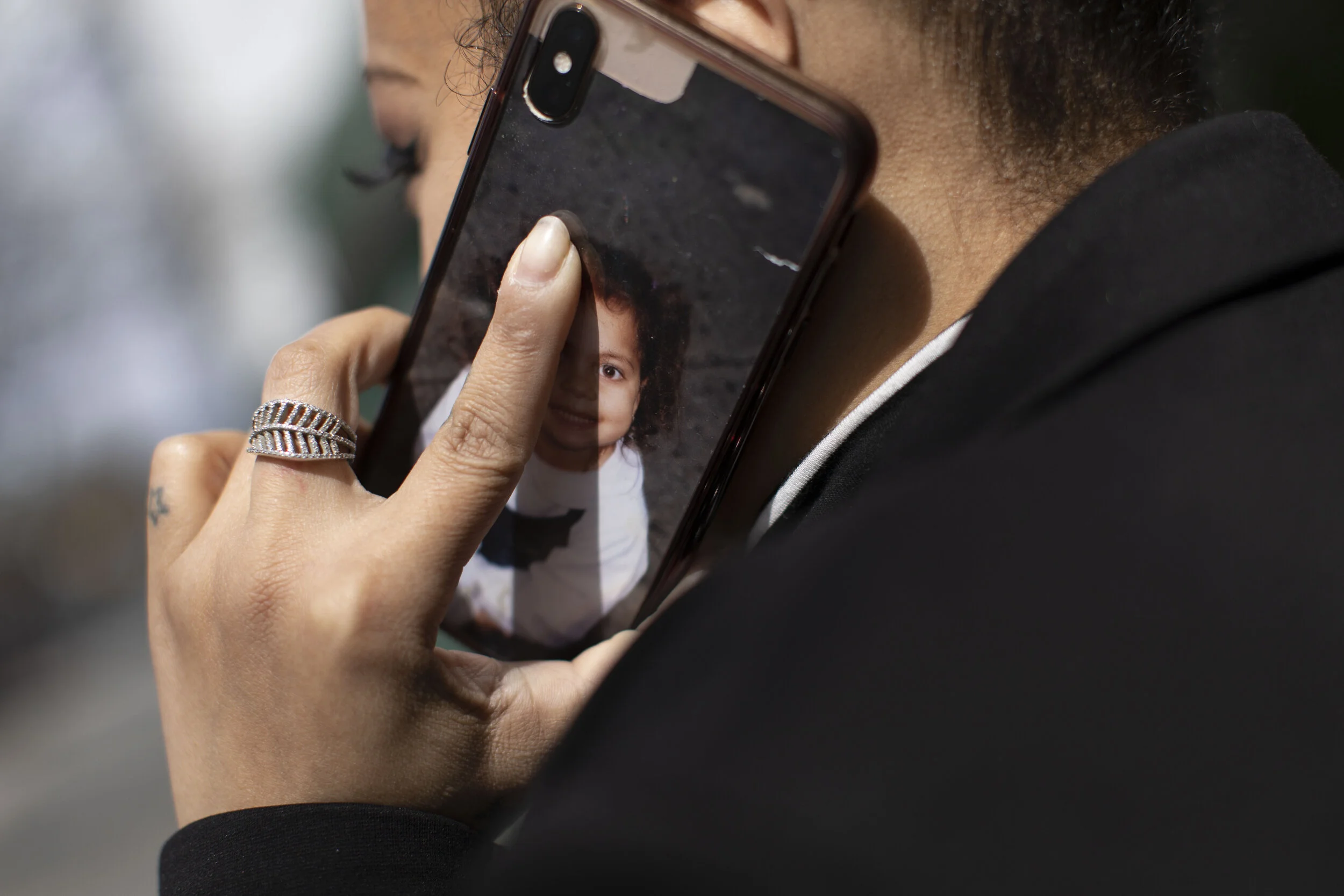  Jenny Adames takes a phone call on her cell phone that features an image of her daughter. Miss Adames insisted that her mother take care of her daughter for a period out of fear that she would contract the disease herself and pass it on to her.  