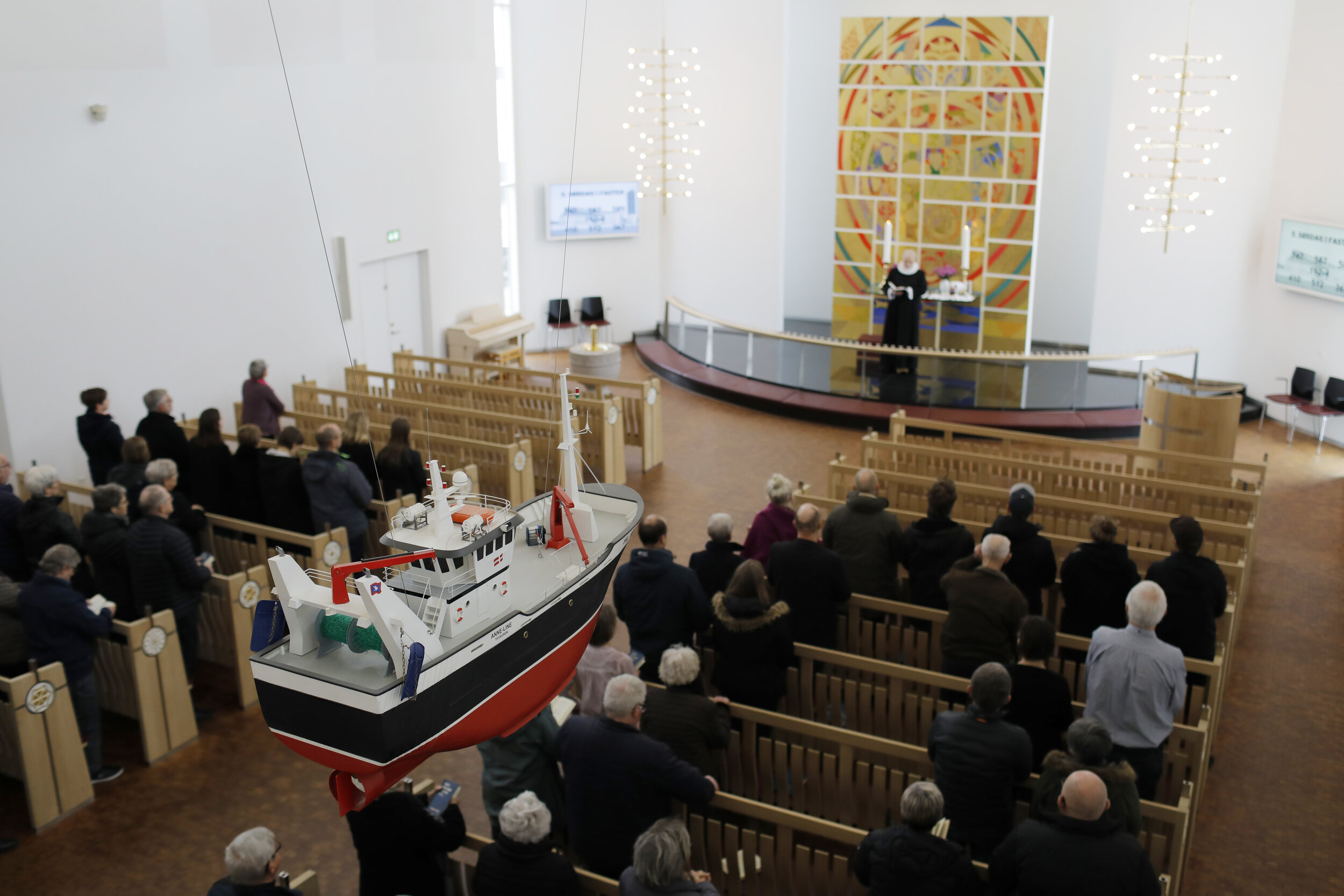  The congregation of the Thyborøn Church gather for their 10 AM Sunday service. A fishing trawler hangs from the church ceiling to remind churchgoers to pray for the town’s fishermen.  