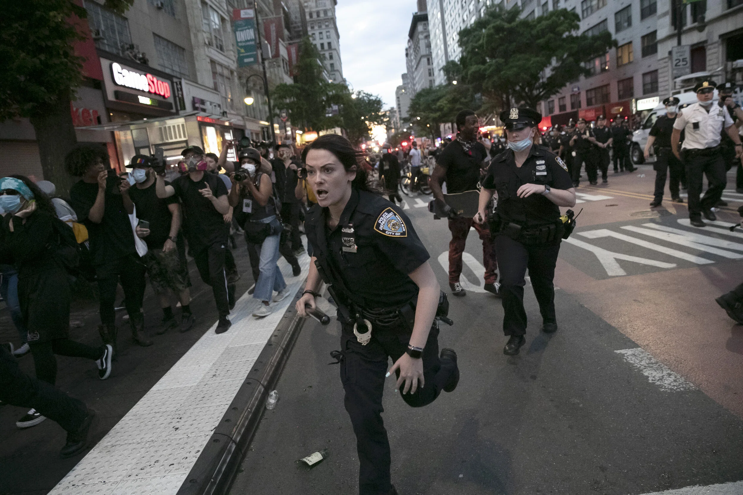  A New York Police Department officer runs at protesters during a demonstration on 14th Street in Manhattan.  
