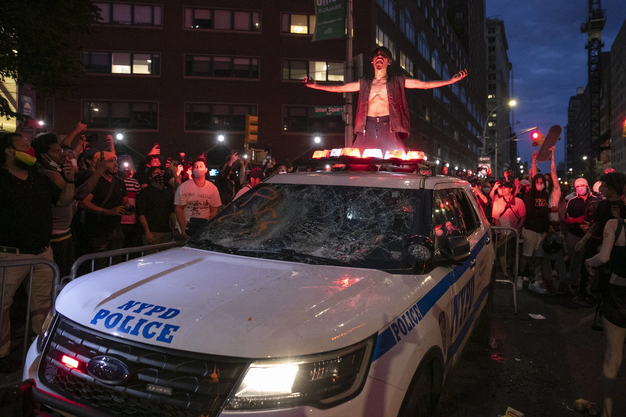  Protesters gather around a police vehicle, damaged by demonstrators on 14th Street in Manhattan.  