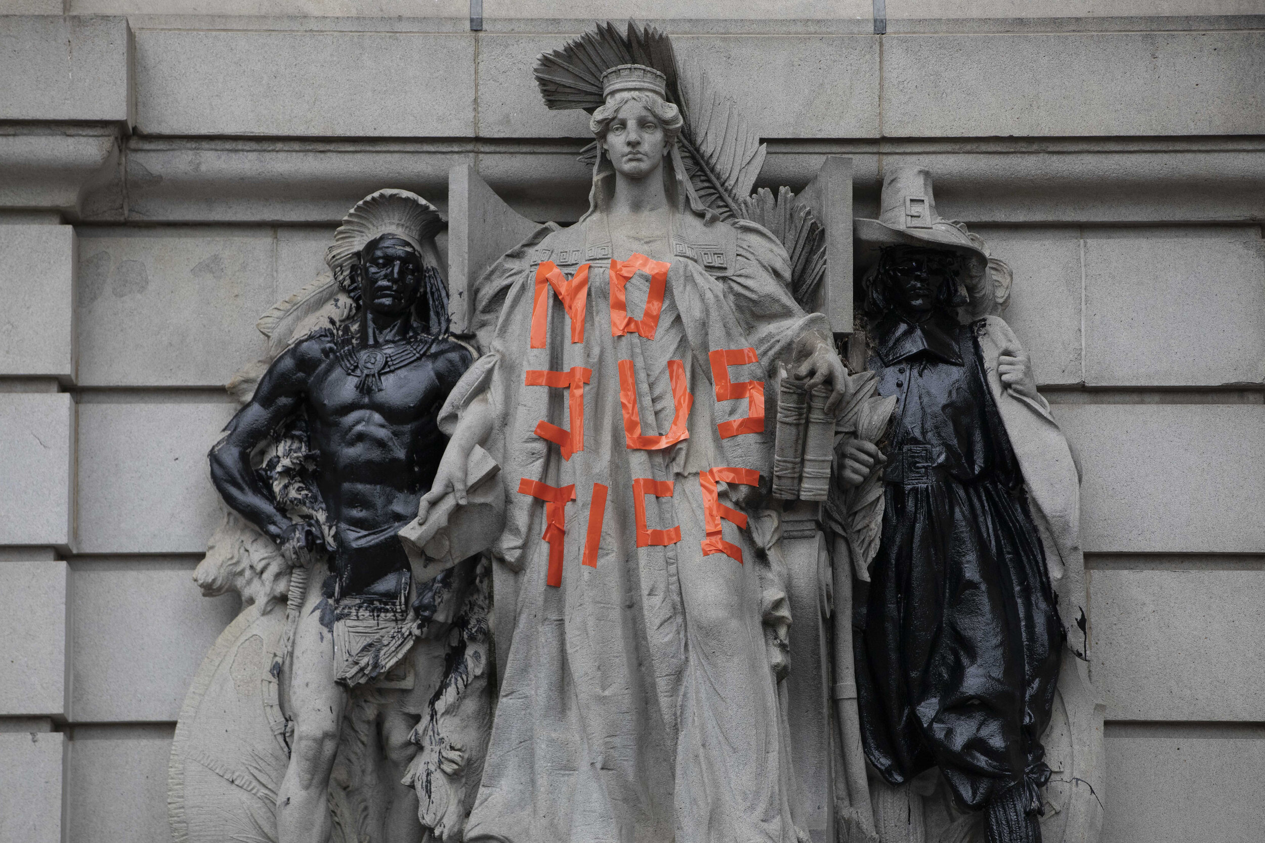  Statues on the exterior of the Surrogate’s Court are seen vandalized. The removal or defacement of statues deemed derogatory became a major aim of B.L.M. protests. 