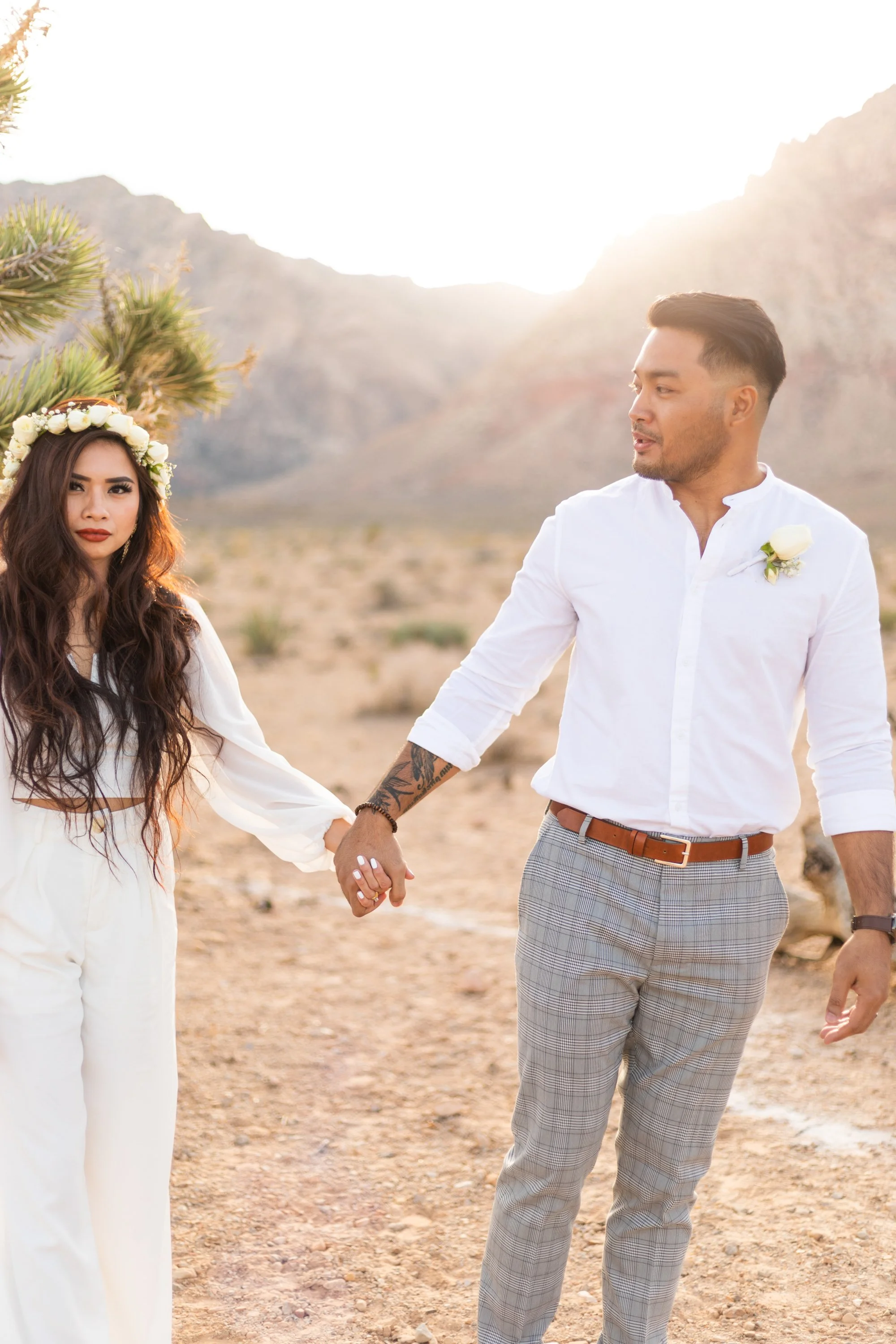 young couple holds hands while the sun sets behind them after they were pronounced married in the Red Rock canyon in Las Vegas