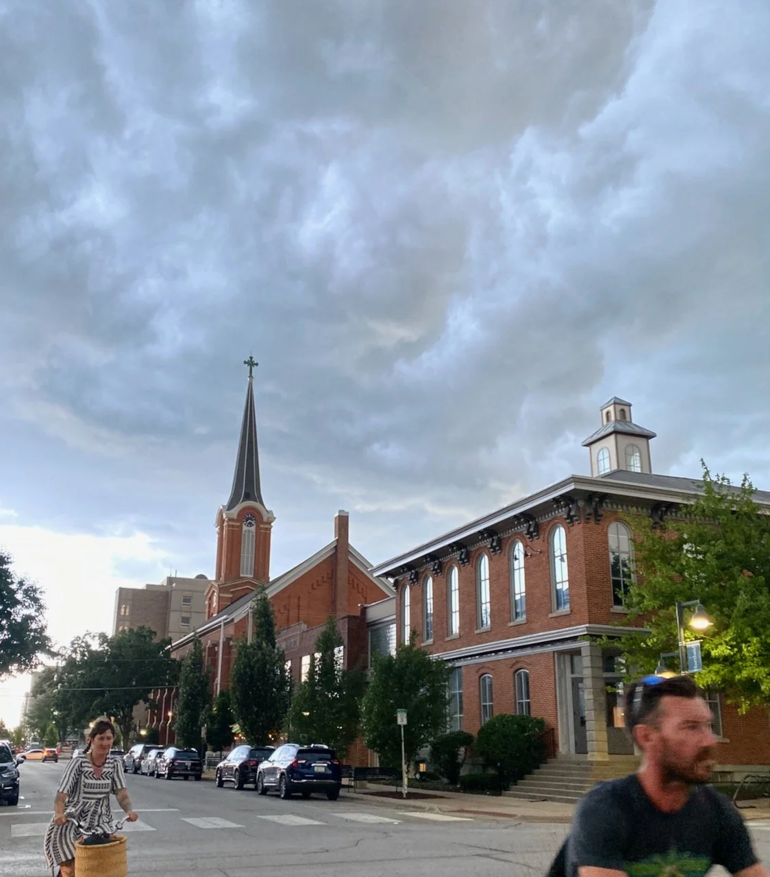 An early evening view of N. Linn Street, looking south at a church spire while two people on bicycles cross Market Street.