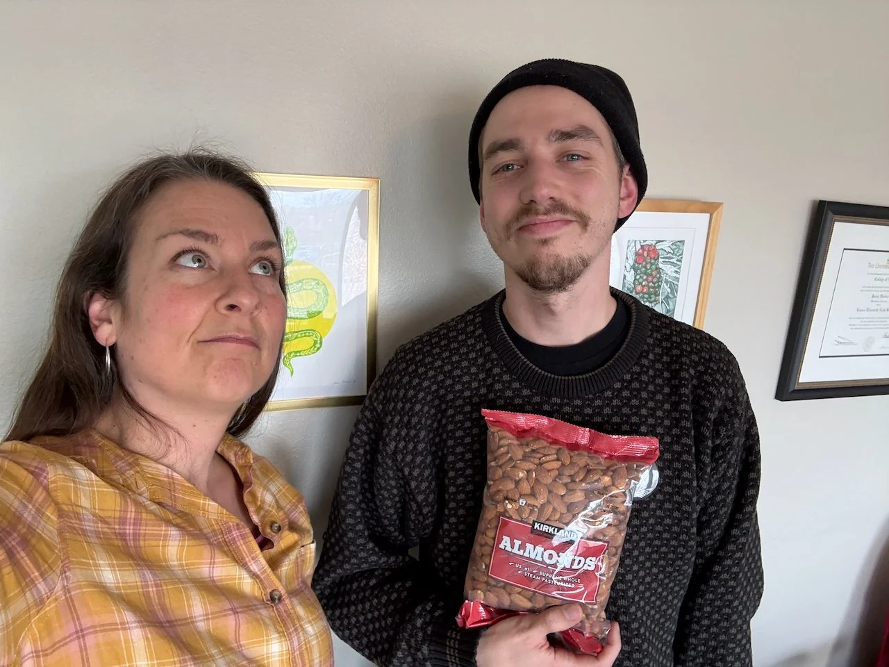 Laura Bergus and Oliver Weilein standing next to each other against a wall with framed art.