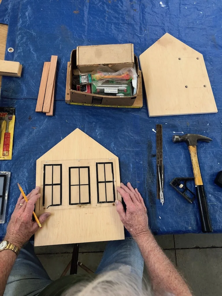 Ron traces windows during repair of a little building