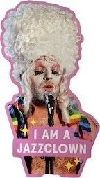 Refrigerator magnet/image of MG from HEAVENS WHAT HAVE I DONE (2010), wearing Marie Antoinette wig, pink, gold and white makeup, fake eyelashes, rainbow collar, singing into mic with I AM A JAZZCLOWN caption.