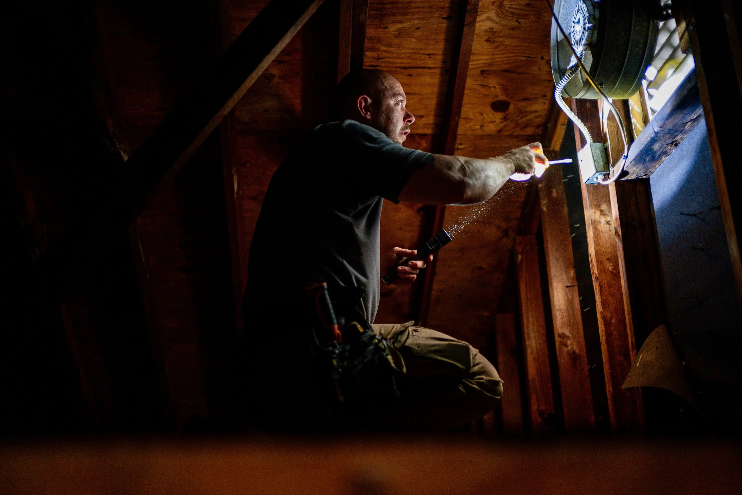 Jacob Knapp inspecting an attic fan and electrical connections during a home inspection.Jacob Knapp inspecting an attic fan and electrical connections during a home inspection.