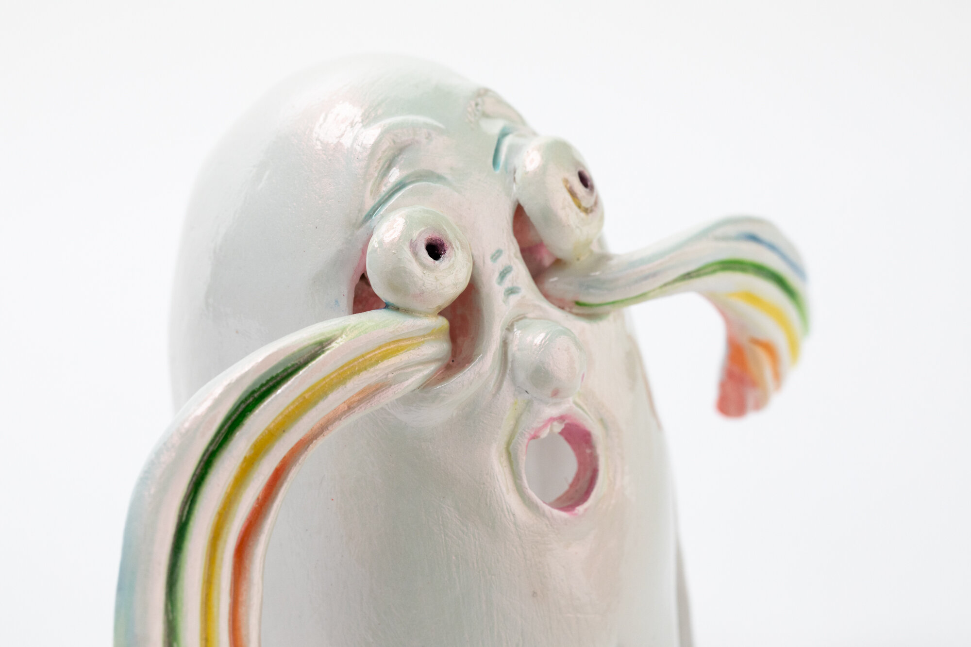 Detail of a painted ceramic sculpture of a ghost crying rainbow tears.