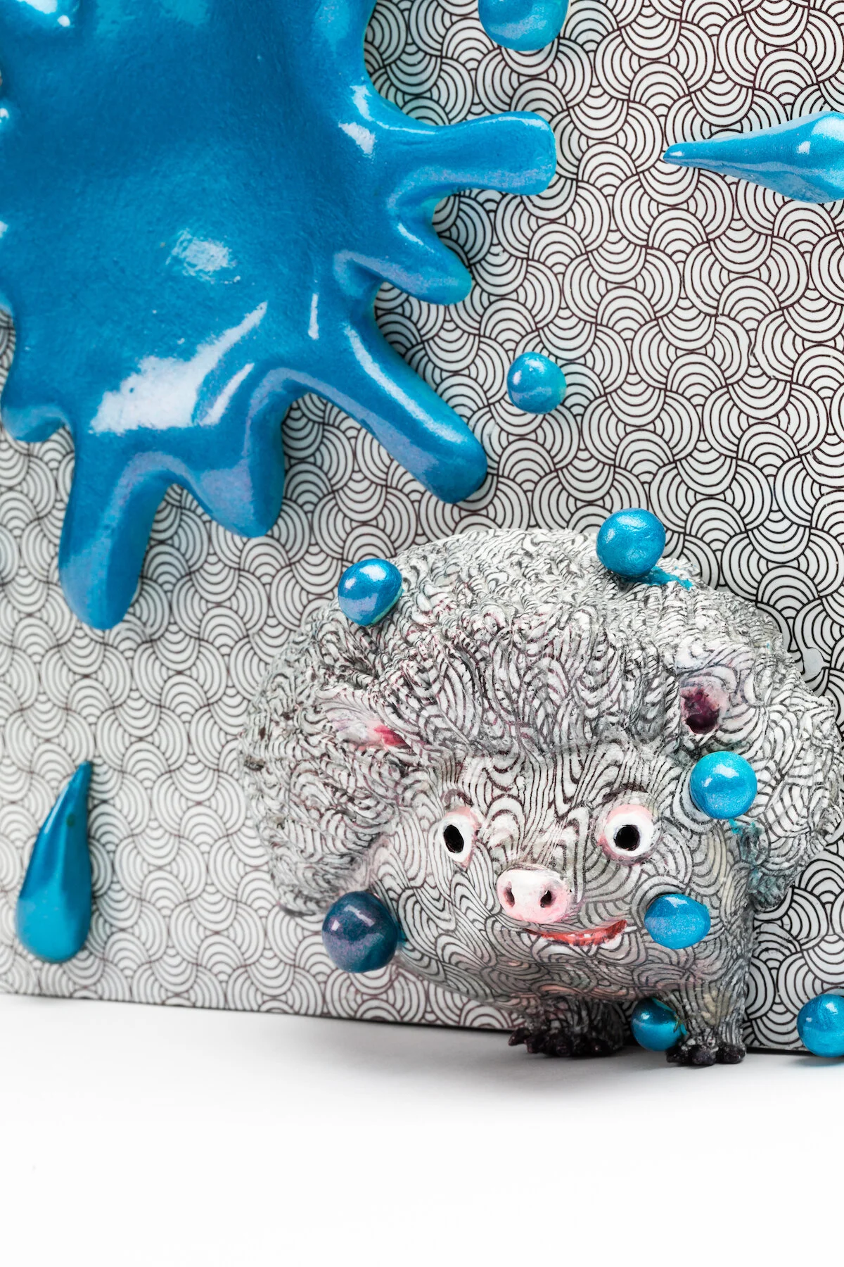 unique ceramic and mixed media sculpture by ceramicist Jennifer McCandless of hedgehog hiding in op art black and white pattern with blue splatters at Soapbox Arts Gallery