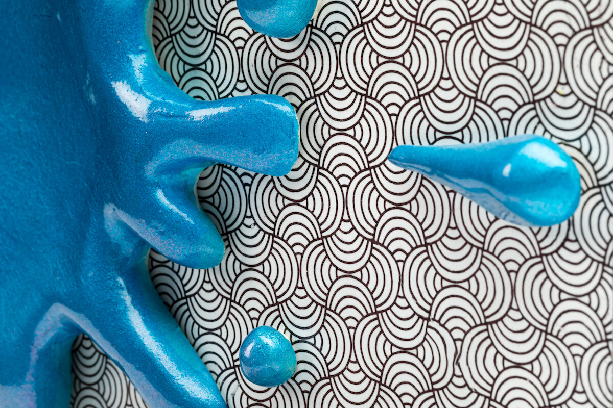 unique ceramic and mixed media sculpture by ceramicist Jennifer McCandless of hedgehog hiding in op art black and white pattern with blue splatters at Soapbox Arts Gallery