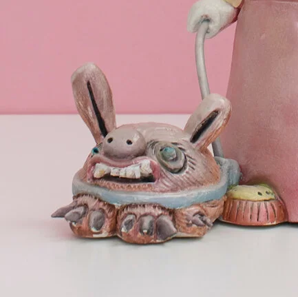 Colorful and hand built ceramic sculpture of a child with a leashed dog holding a number of balloons on strings with monster faces by Jennifer McCandless for Soapbox Arts