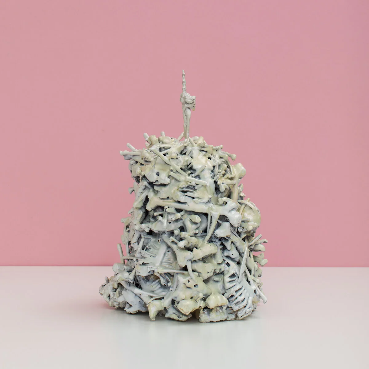 original hand built and painted ceramic sculpture by Jennifer McCandless of a pile of bones with arm sticking out of the top giving the middle finger, available exclusively through Soapbox Arts