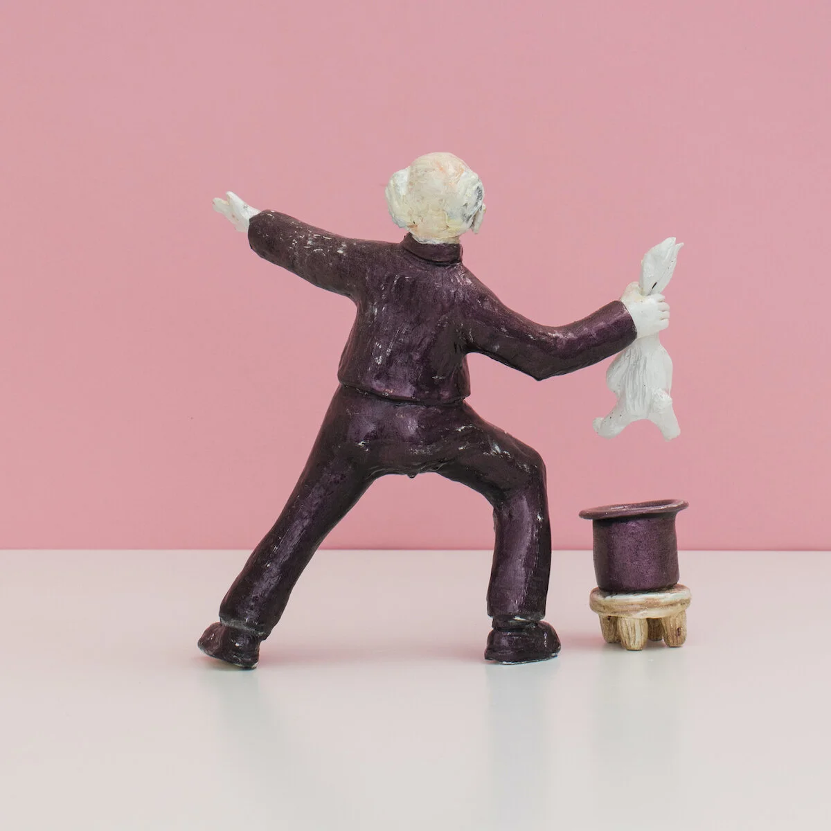 humorous hand built and painted ceramic sculpture of a man dressed as a priest pulling a rabbit out of a hat by Jennifer McCandless available through Soapbox Arts