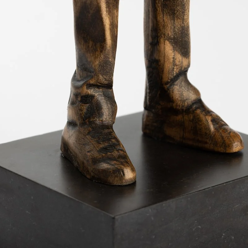 Original anthropomorphic sculpture in stained wood on a stone base of a hare wearing a puffy vest and jeans by Vermont artist and sculptor, Joe Lupiani, available @ Soapbox Arts Gallery in Vermont