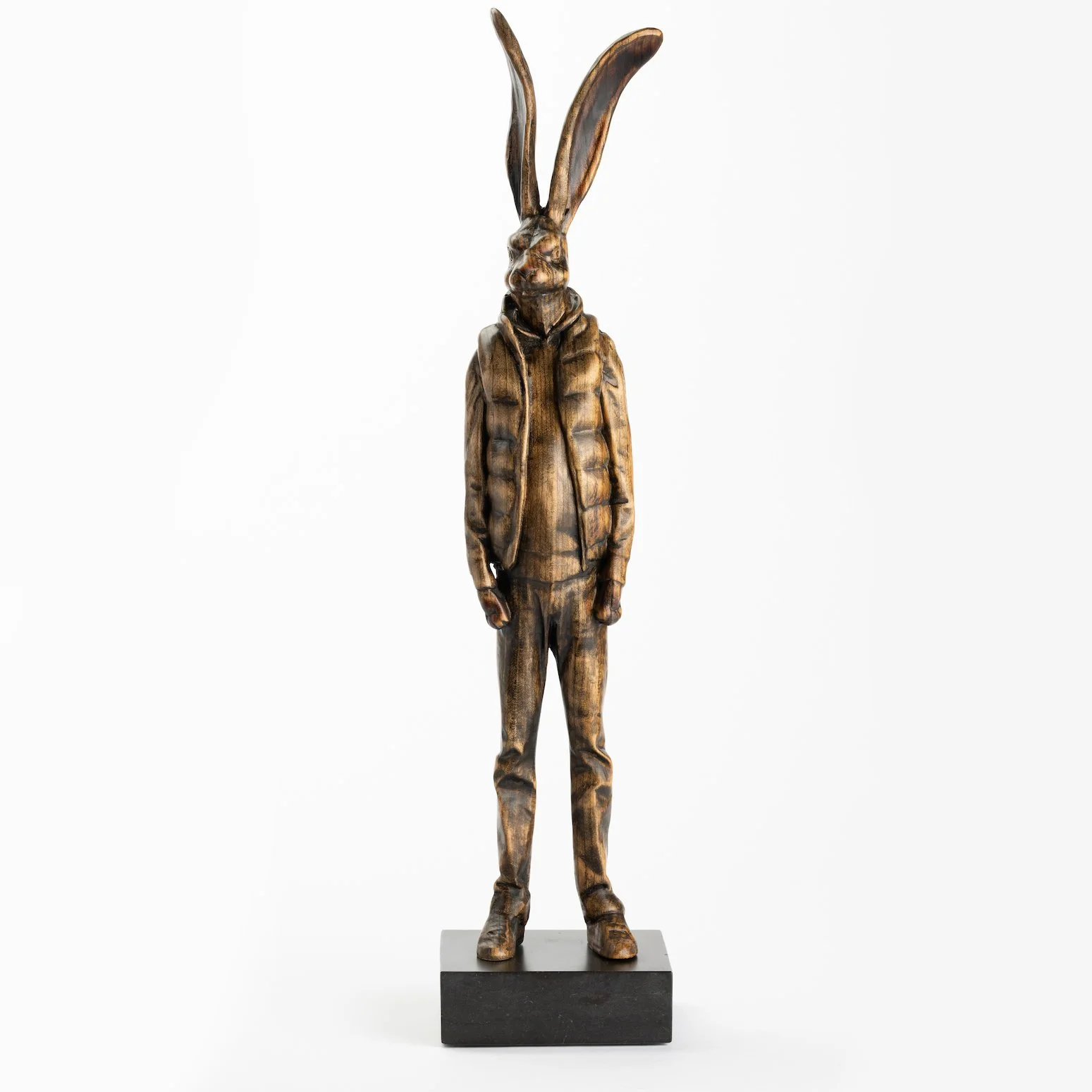 Original anthropomorphic sculpture in stained wood on a stone base of a hare wearing a puffy vest and jeans by Vermont artist and sculptor, Joe Lupiani, available @ Soapbox Arts Gallery in Vermont