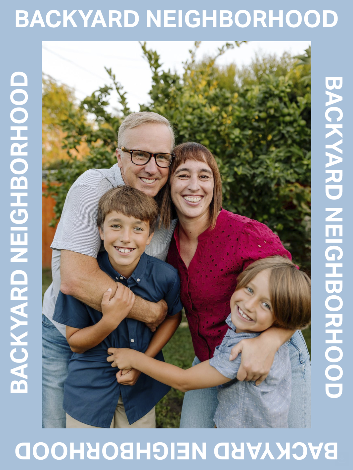 A family of four smiling and hugging outdoors in a backyard with greenery and trees.