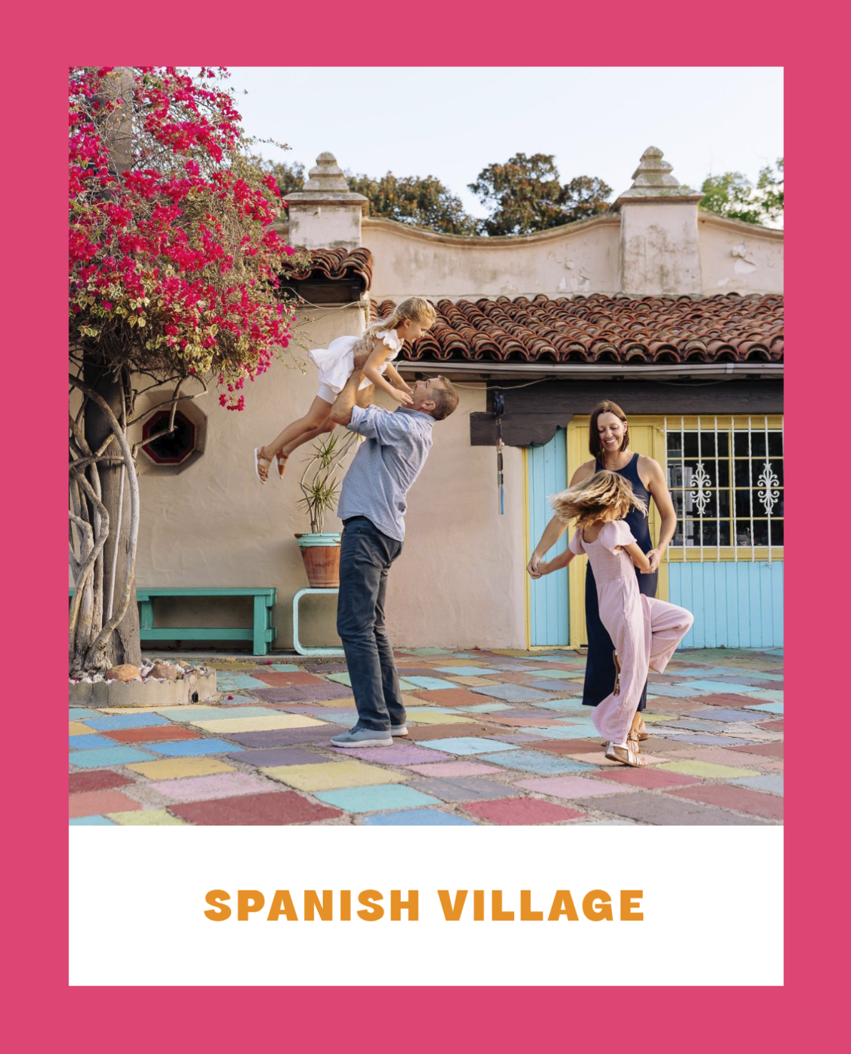 A family playing in a colorful outdoor courtyard in The Spanish Village at Balboa Park, with pink flowering tree and traditional architecture.