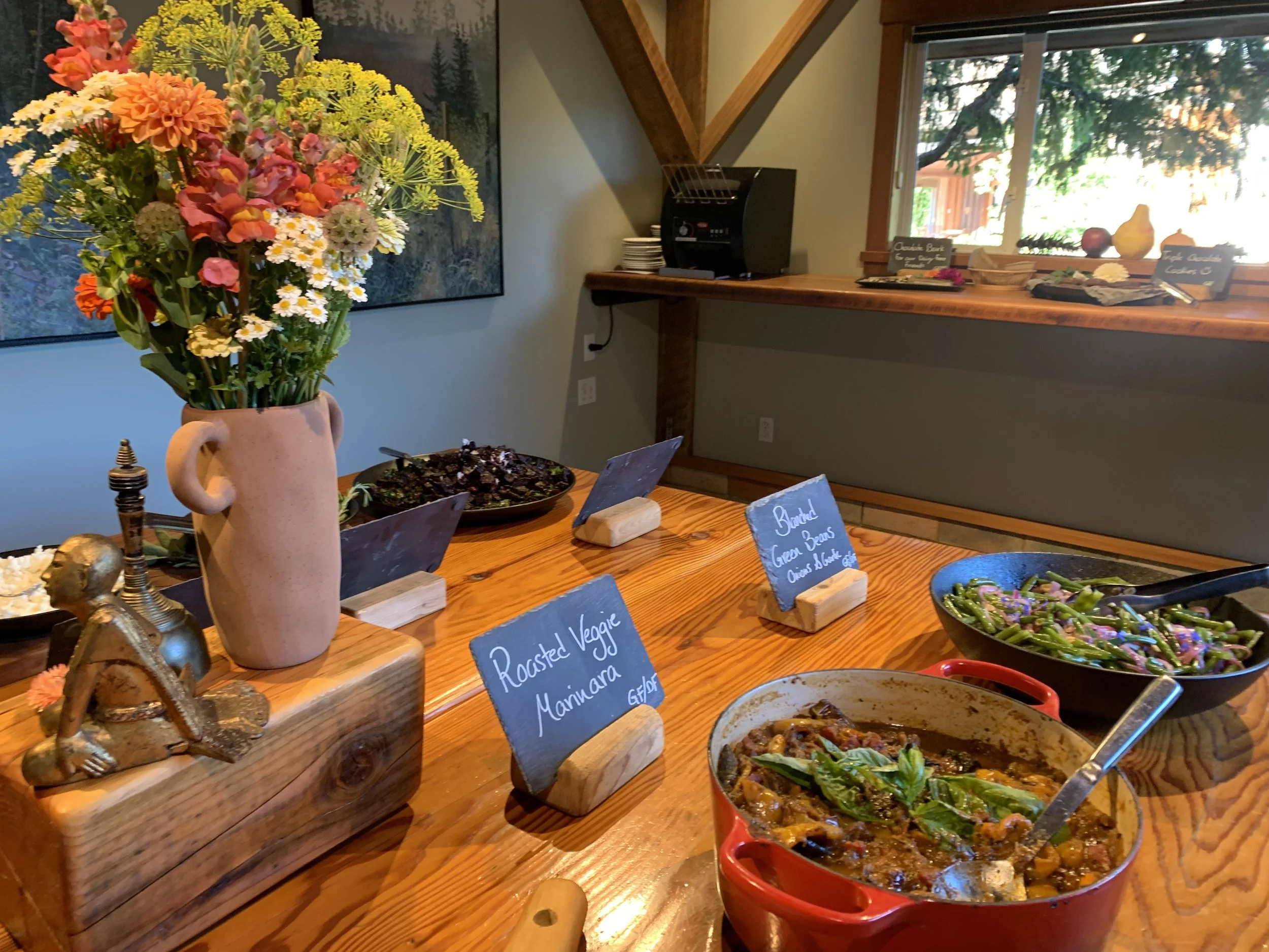 healthy dishes on a table with name cards and a bunch of flowers in a teracotta jug