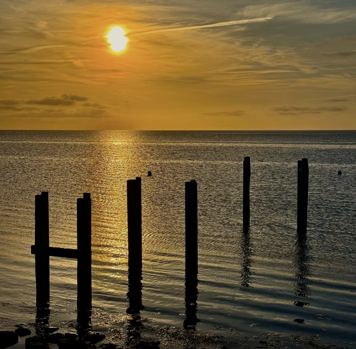 sunset over ocean with wooden pier on terschelling island
