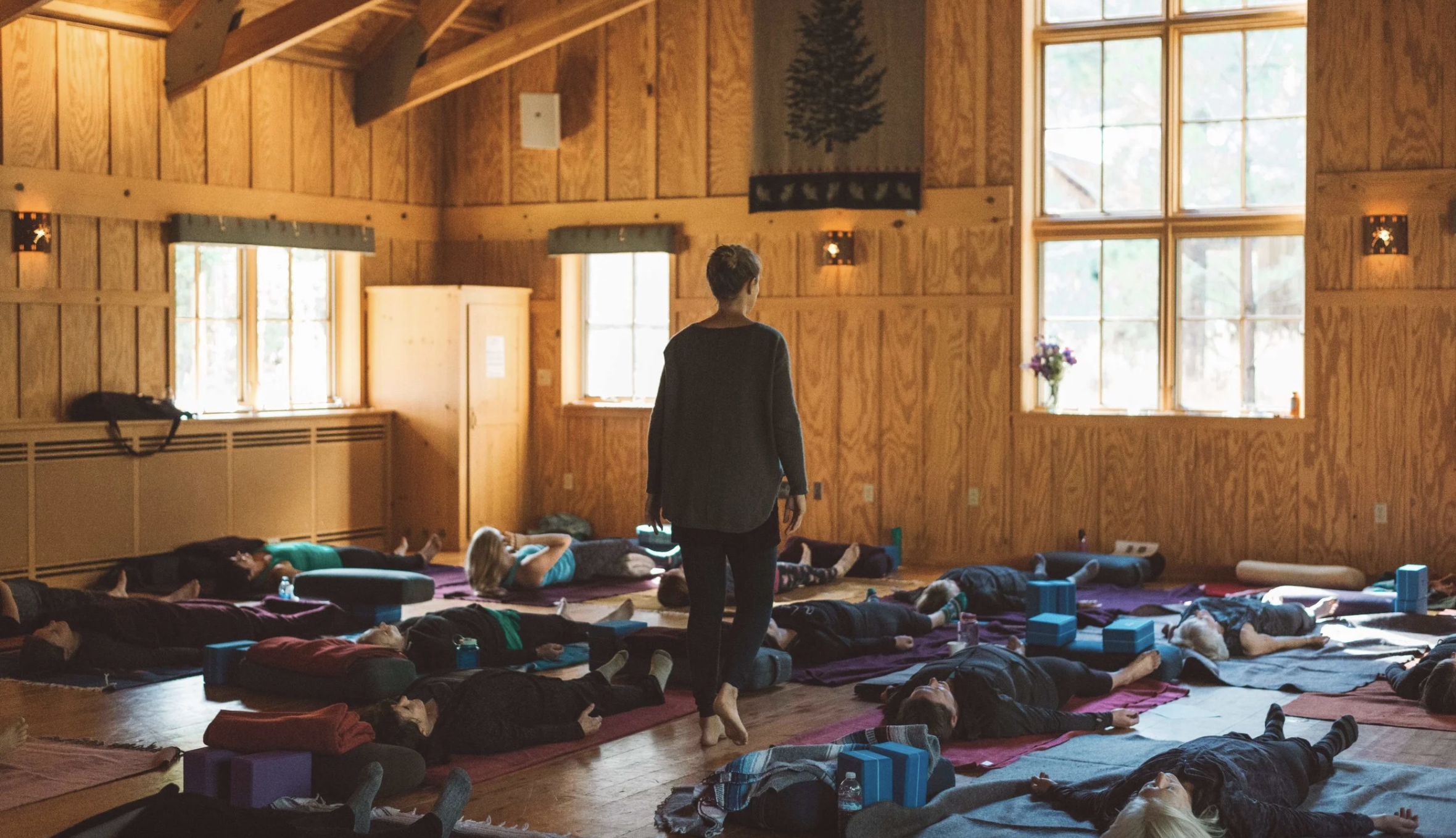 yoga daylong retreat workshop people lying on the floor yoga teacher walking amongst them