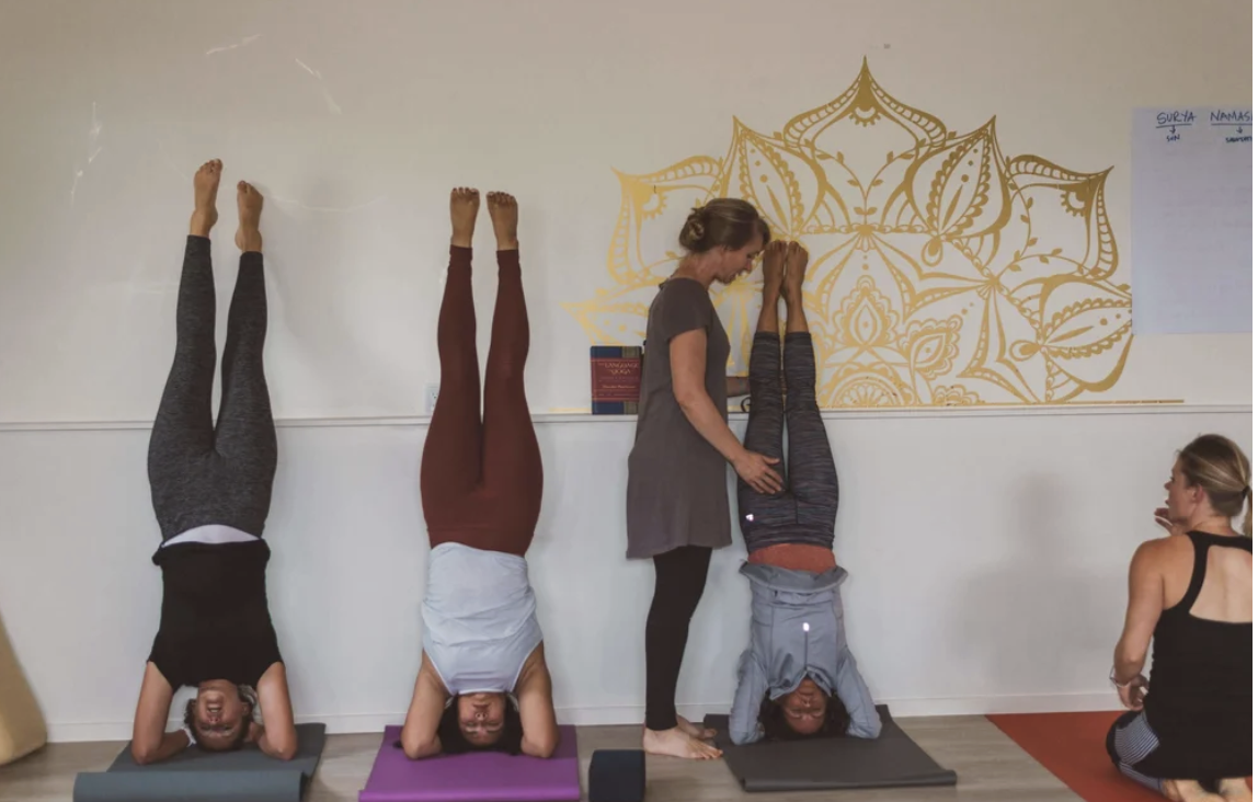 yoga teacher helping someone with a headstand
