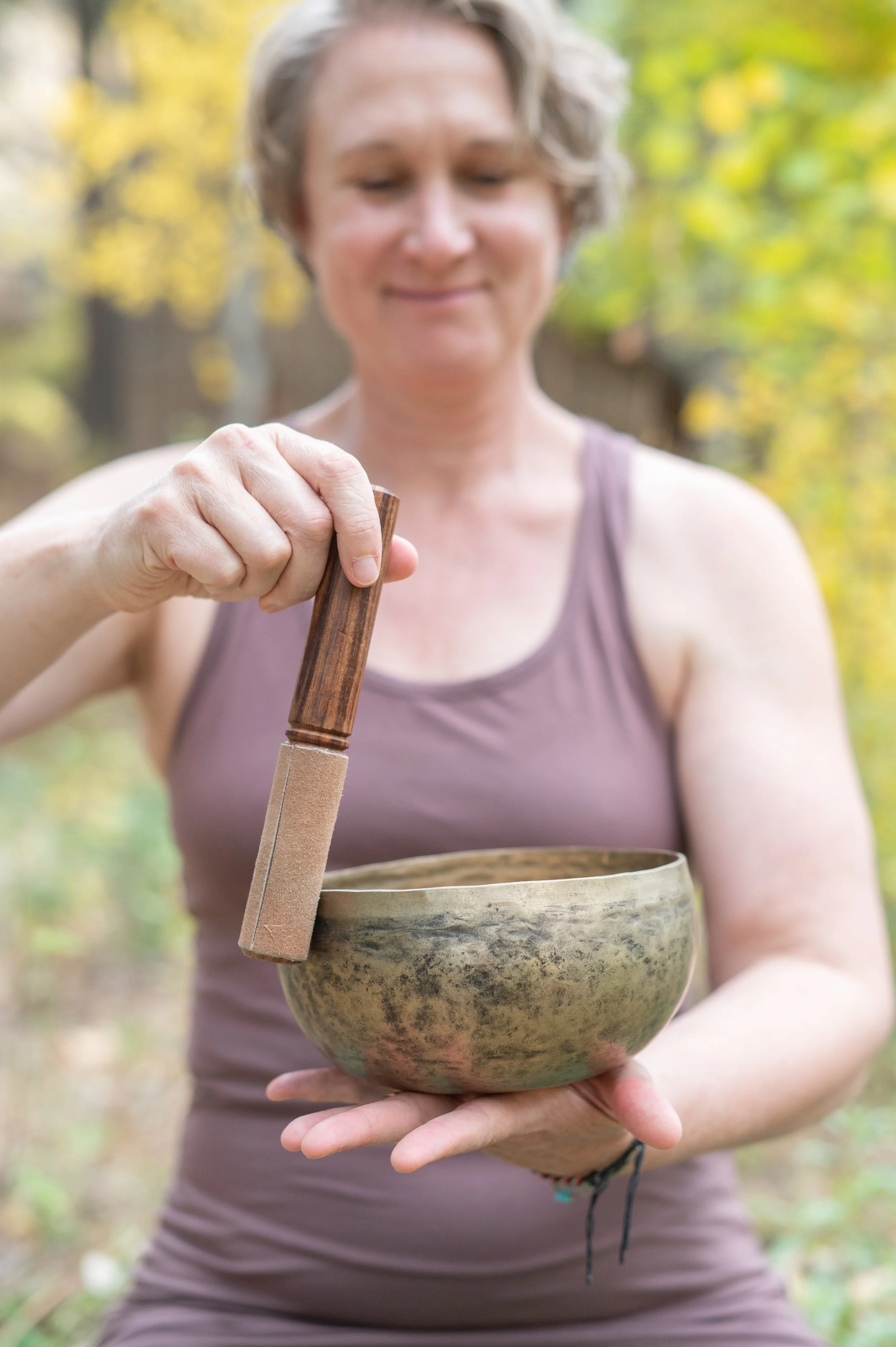 joanna dunn yoga wearing workout clothes and holding a bowl for a sound bath