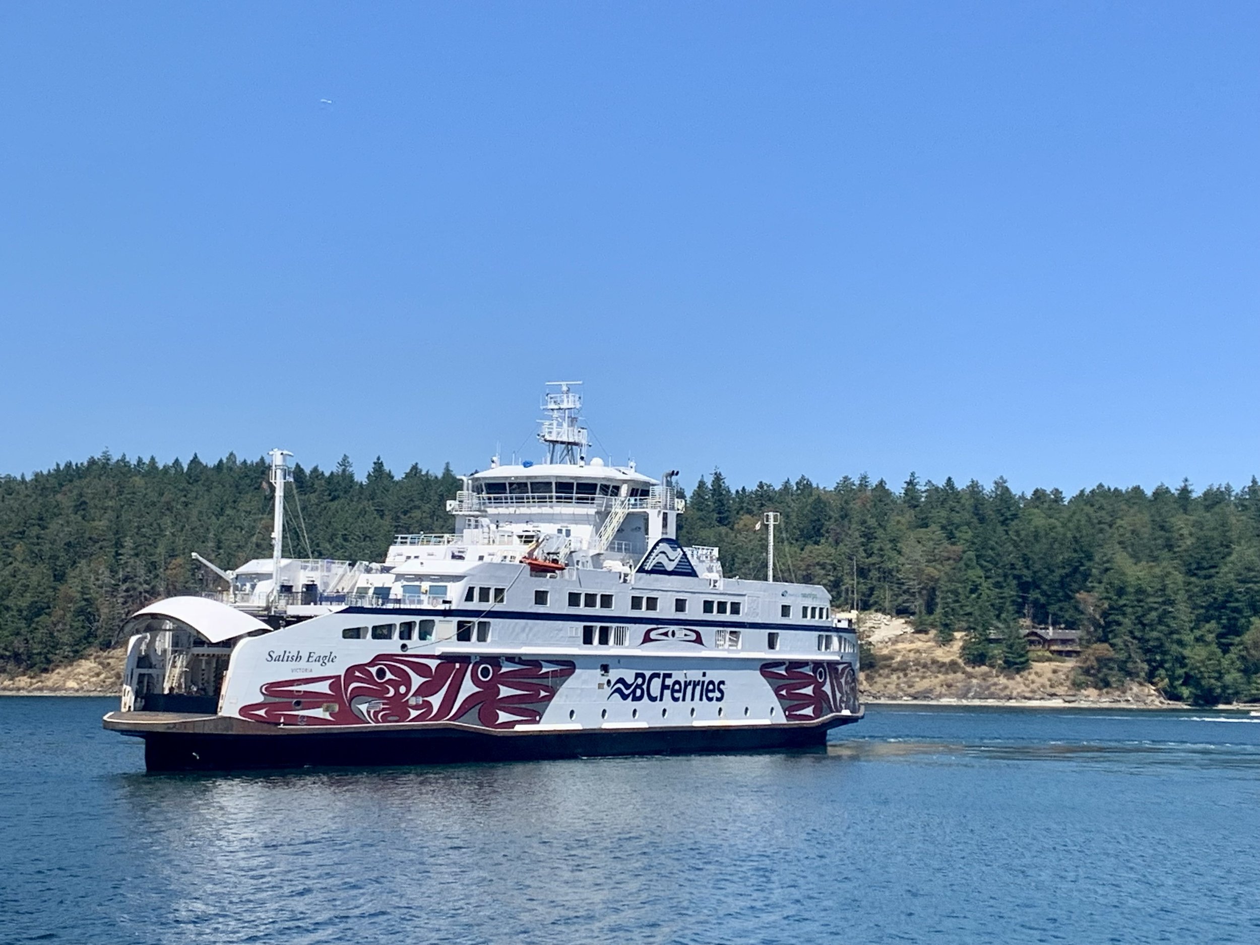 salt spring island ferry on water with blue sky and forest in background