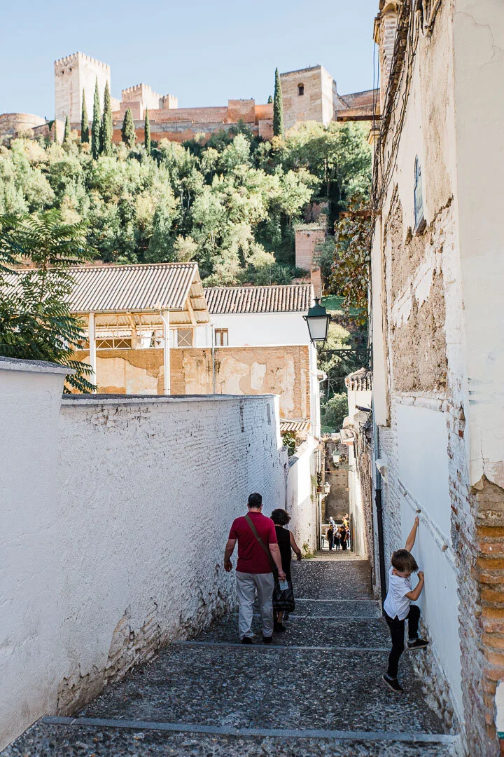 Narrow alley of the Albaicin neighborhood with the Alhambra palace above.