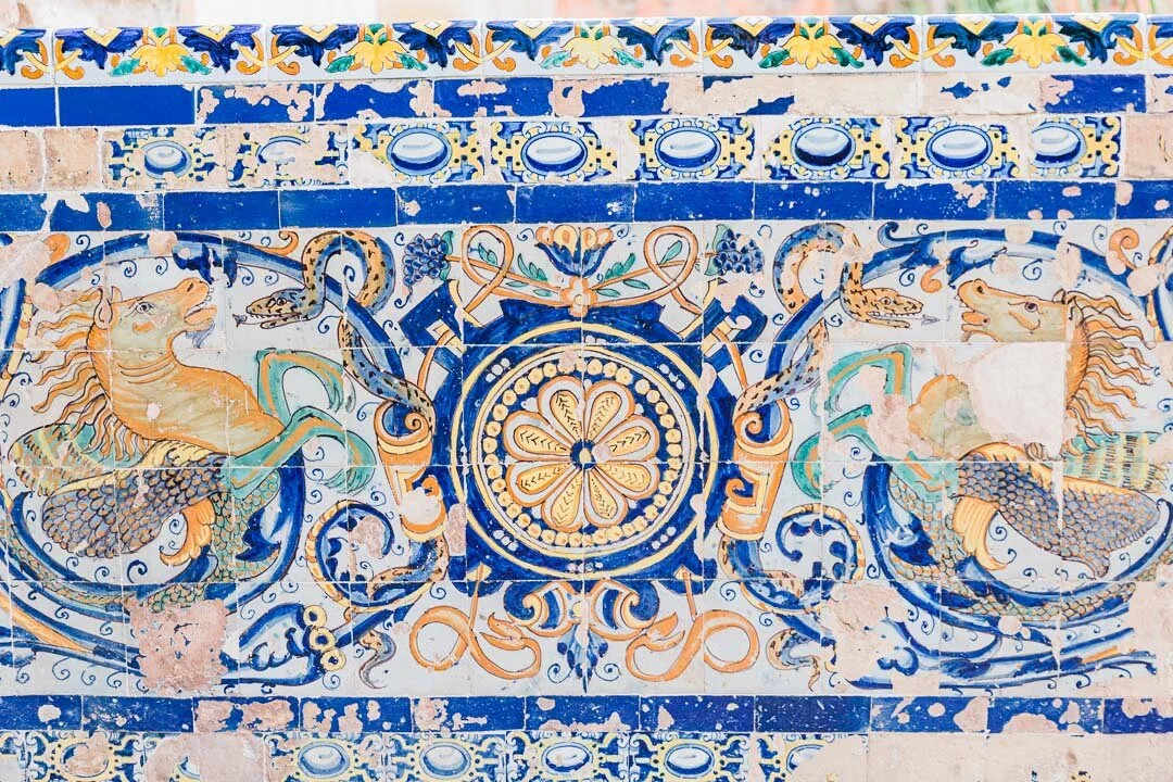 Painted tile work depicting snakes and horses, some of the tiles chipped and damaged, at Reál Alcazar in Seville, Spain.