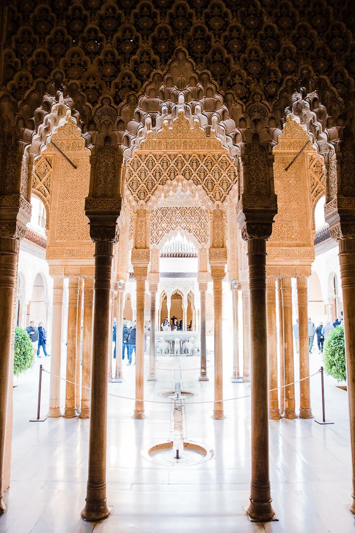 Lion courtyard and fountain through the intricately carved archways at the Alhambra palace in Granada, Spain.
