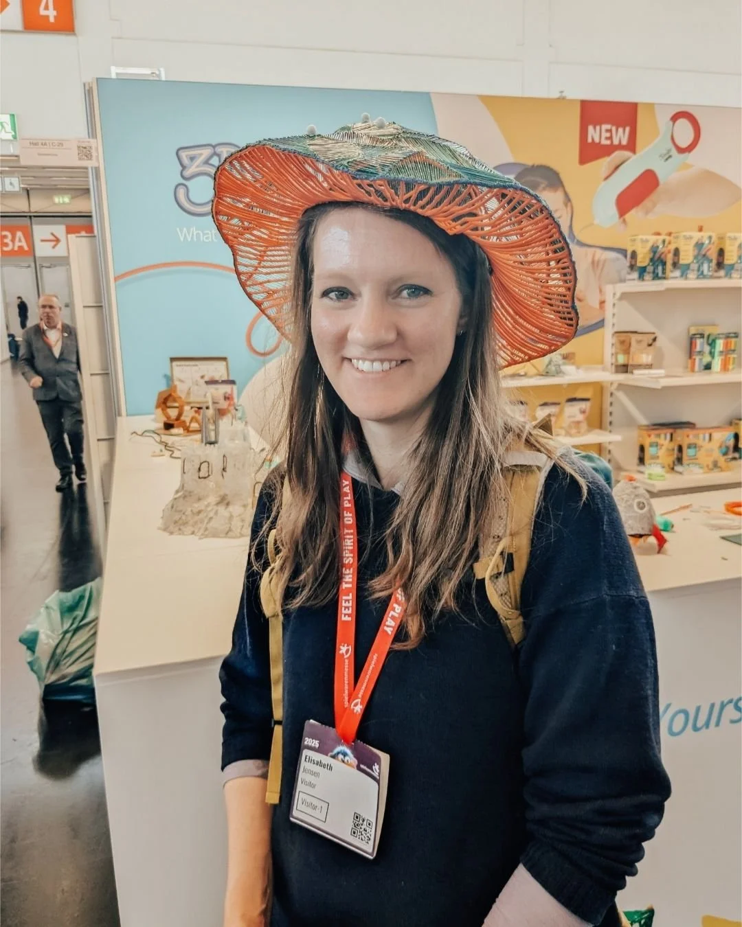 Woman in black shirt wearing a lanyard and a woven hat smiling at the camera