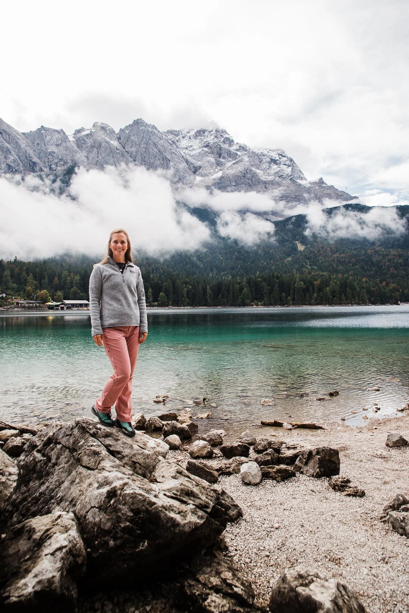 Woman standing on the rocks by Eibsee with mountains in the background in Garmisch, Germany
