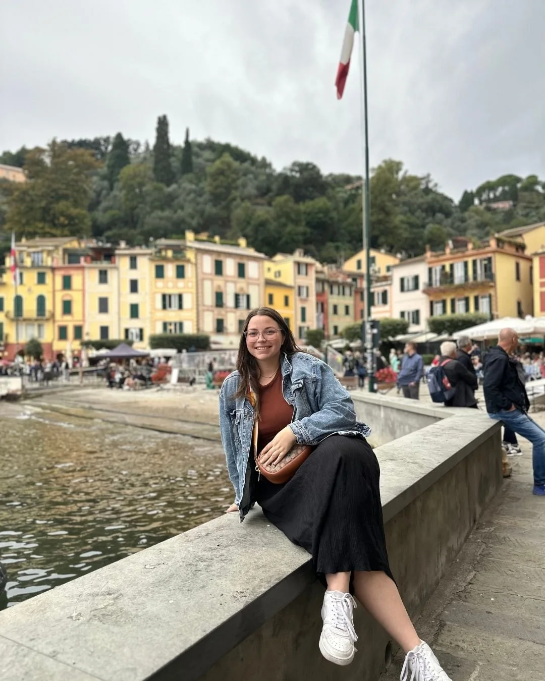 Woman sitting on a seawall in a colorful Italian village