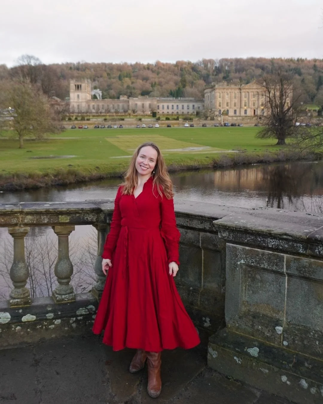 Woman in red dress standing in front of an English castle