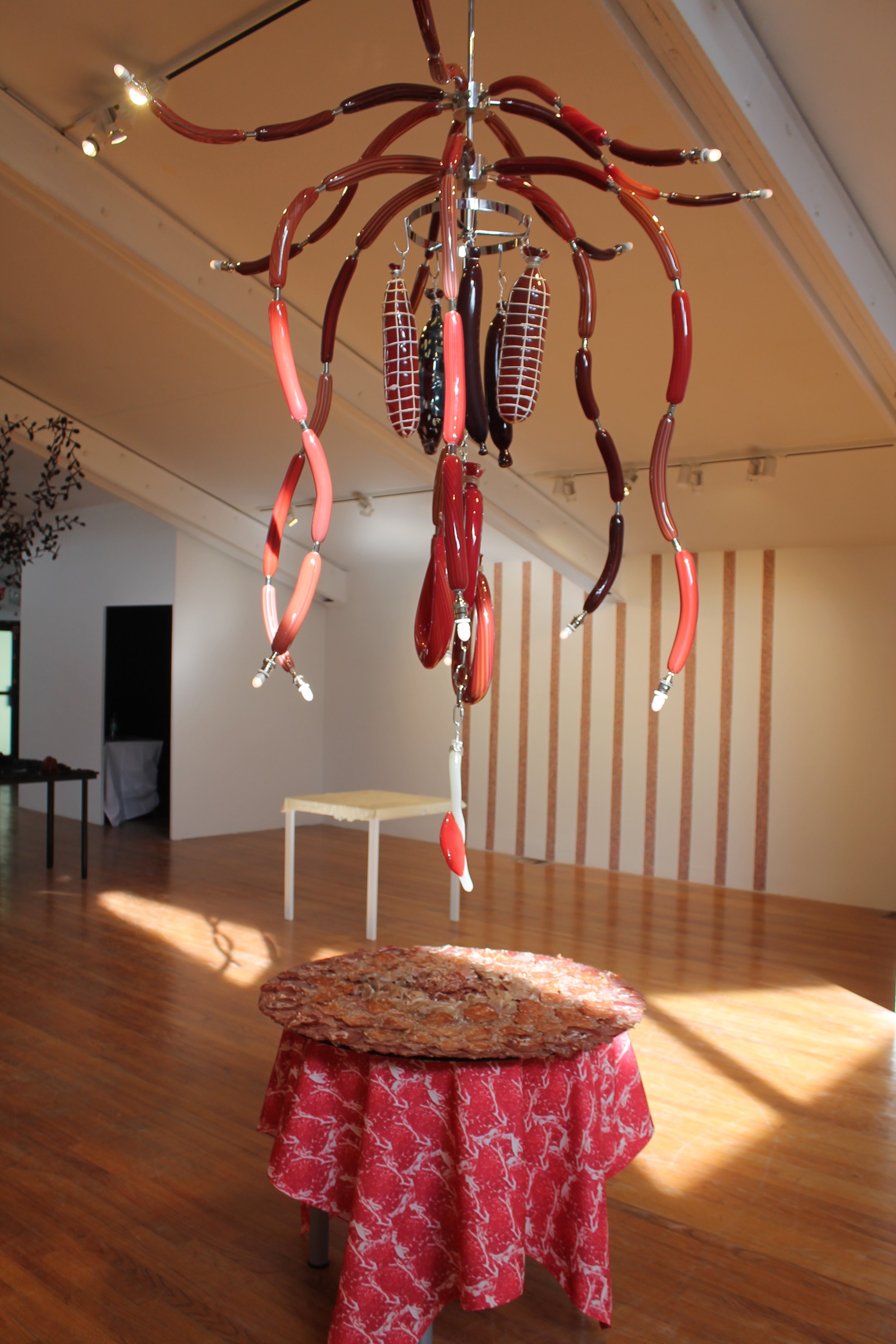 Deborah Czeresko's Meat Chandelier for How Shall We Dine? sitting over cured meats and blown glass cutlery