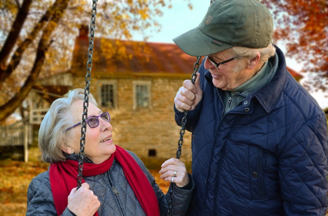 A happy, active older couple. The woman is on a swing.