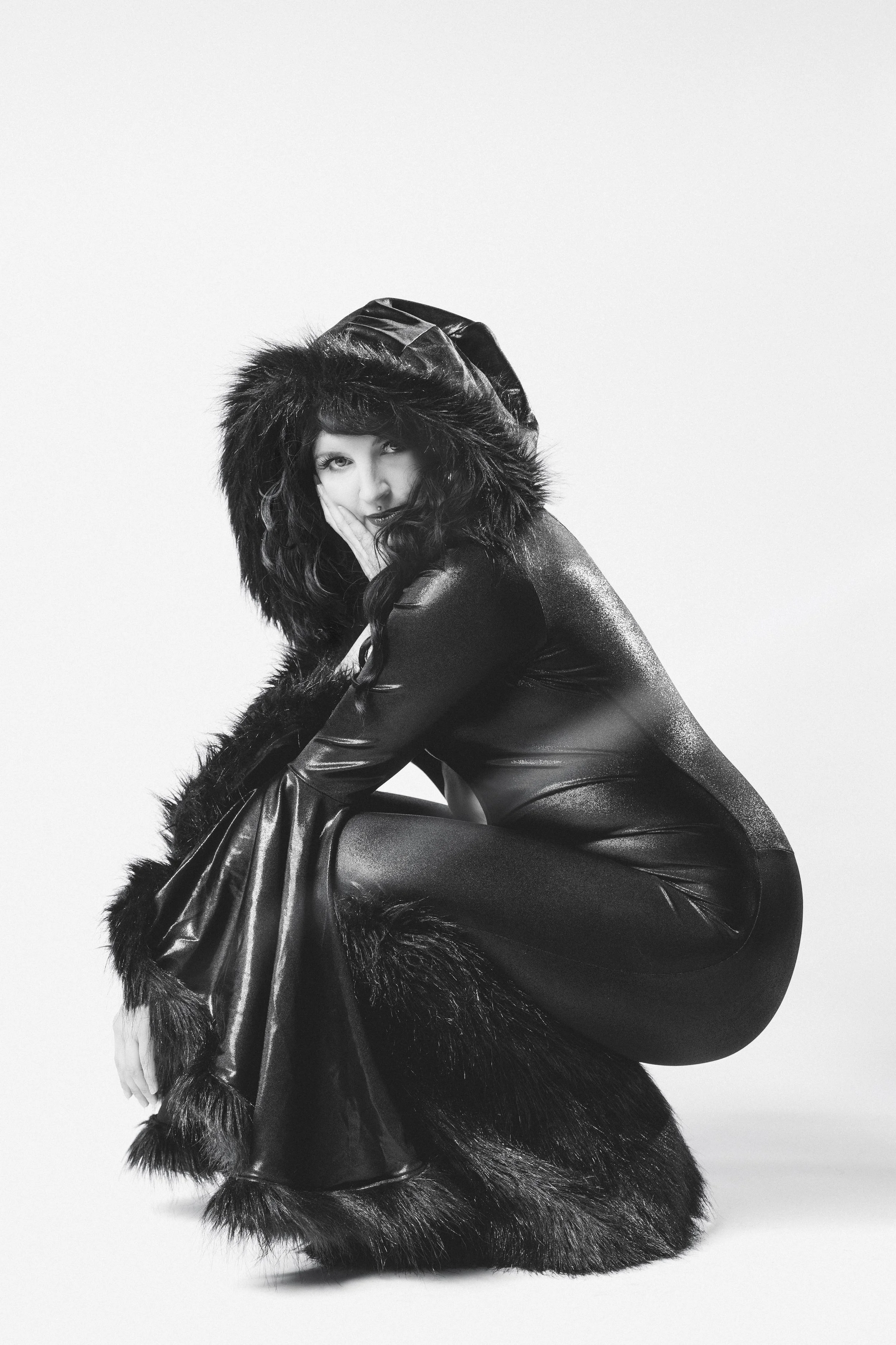 Black and white photo of a model wearing a fur-lined hooded jumpsuit