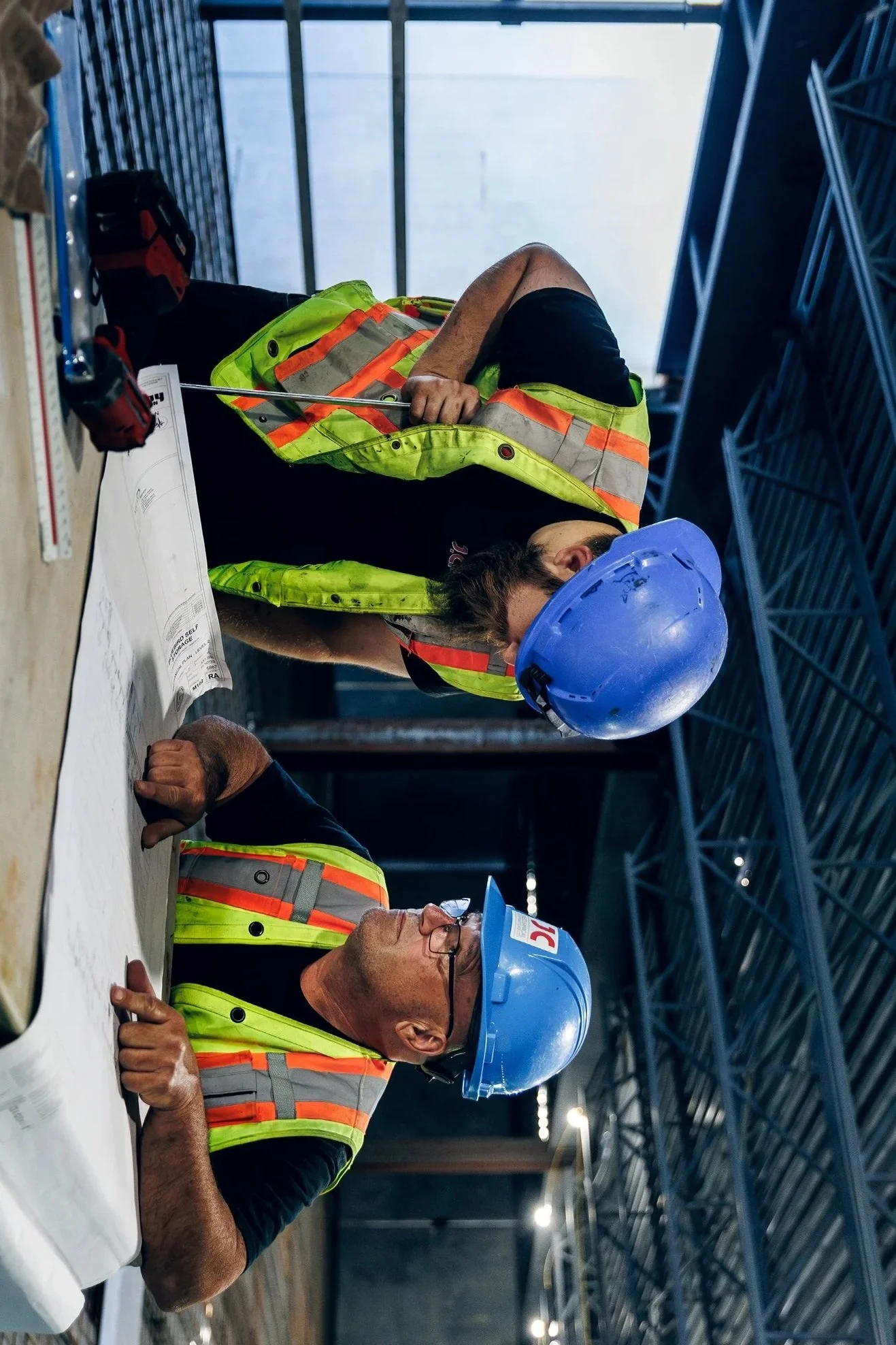 Two construction workers looking over blueprints for a concrete project