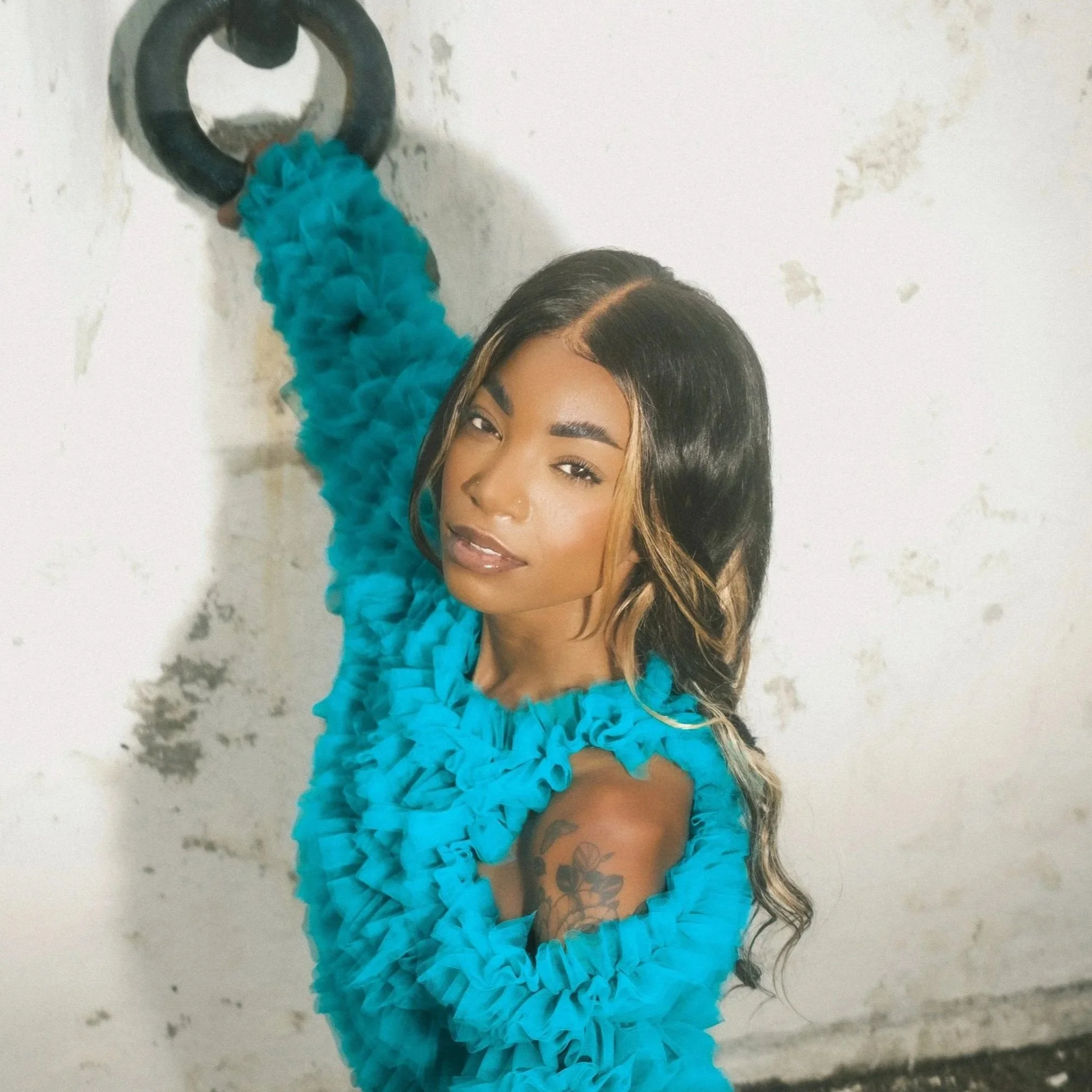 High fashion portrait of a model wearing a frilled turquoise shirt 