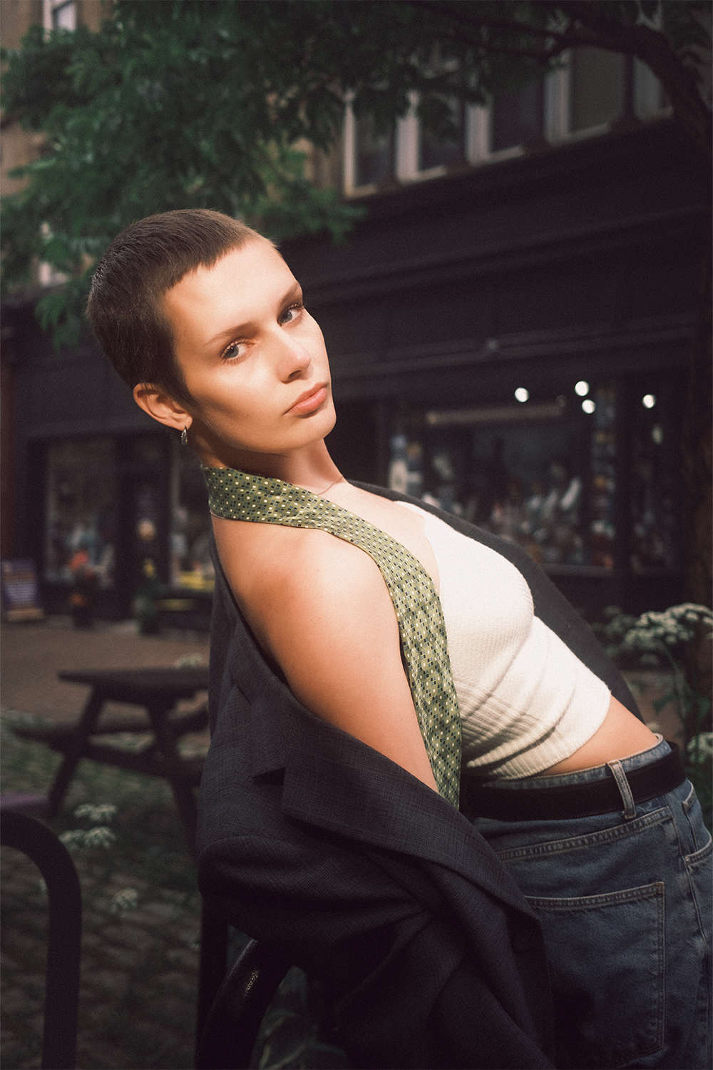 A fashion model with short hair poses with an exaggerated lean while looking at the camera