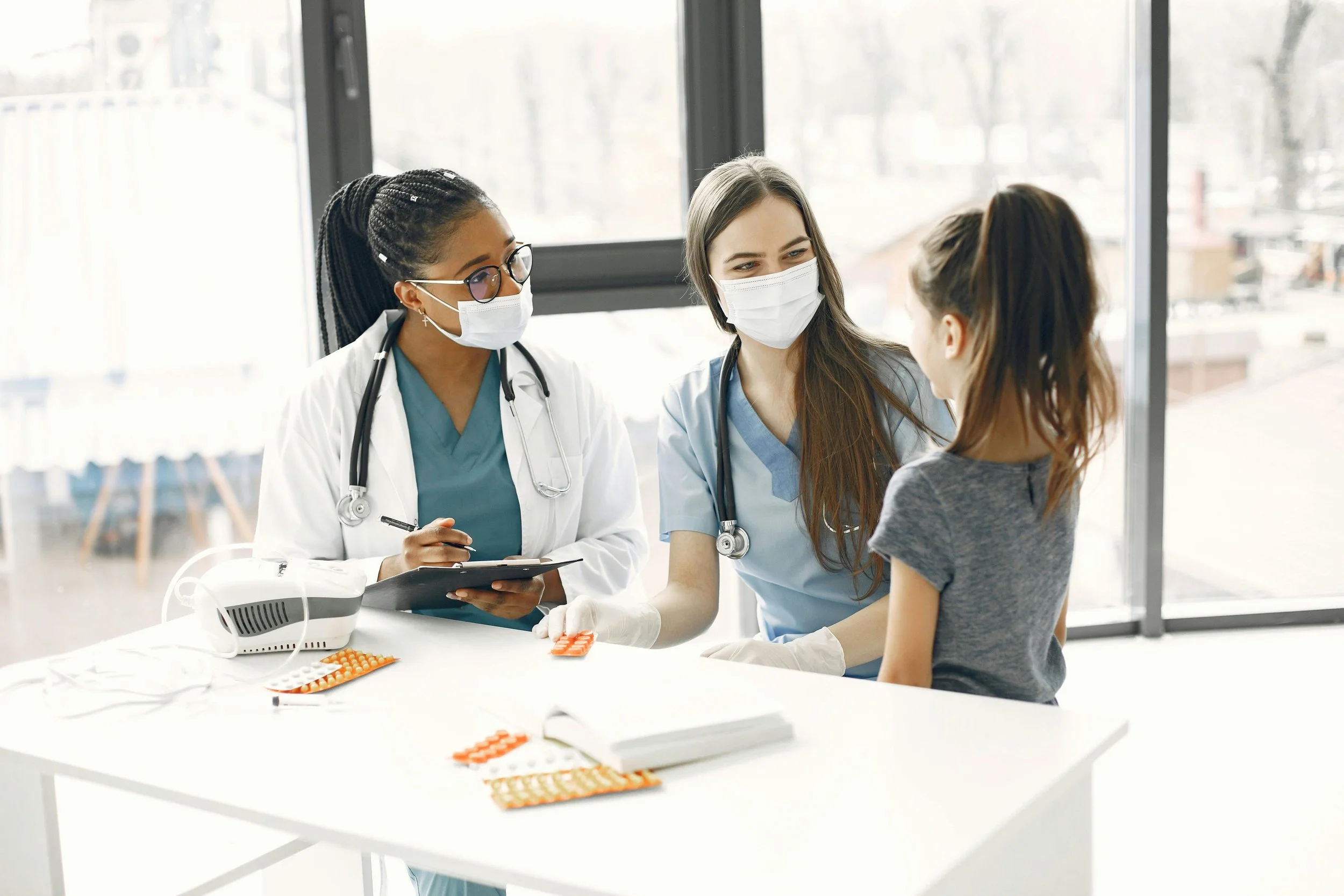 Doctor and nurse sit next to a young girl patient