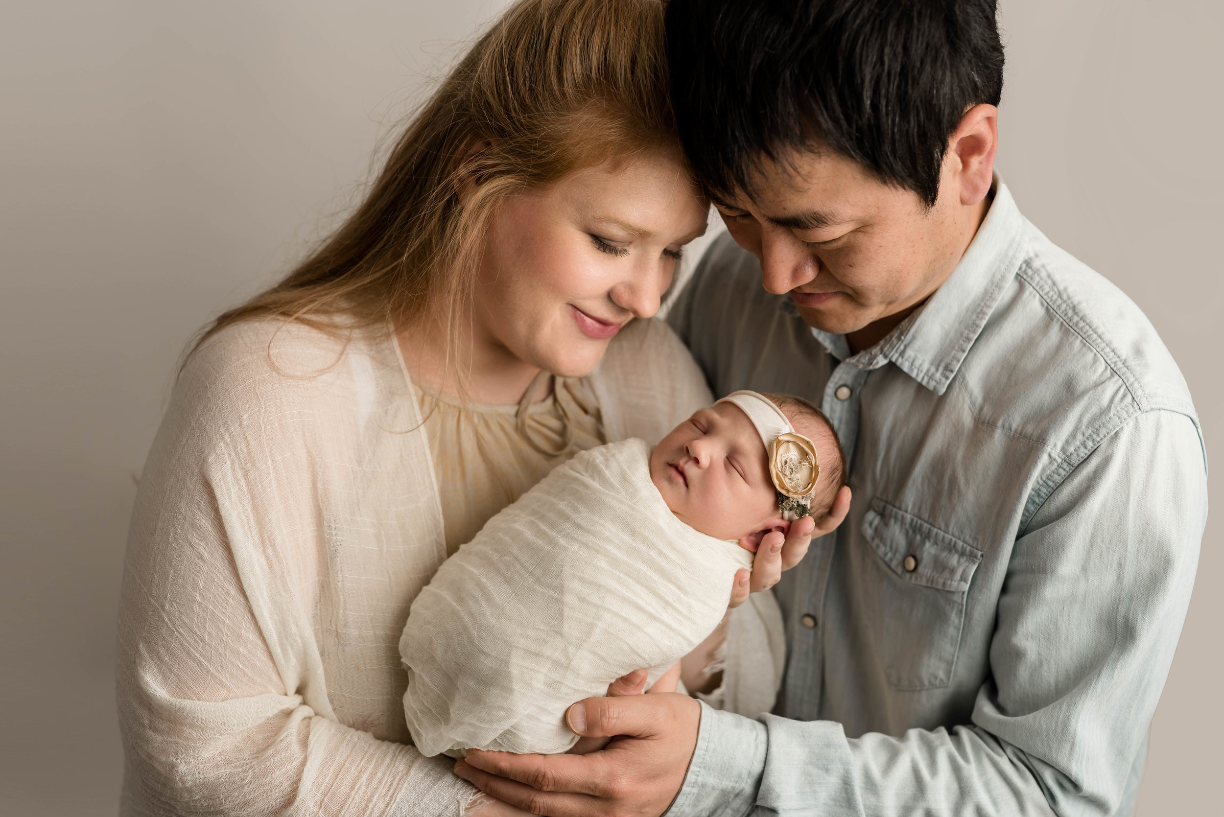 korean american family loving on their new baby girl at junebug photography studio in manhattan, kansas