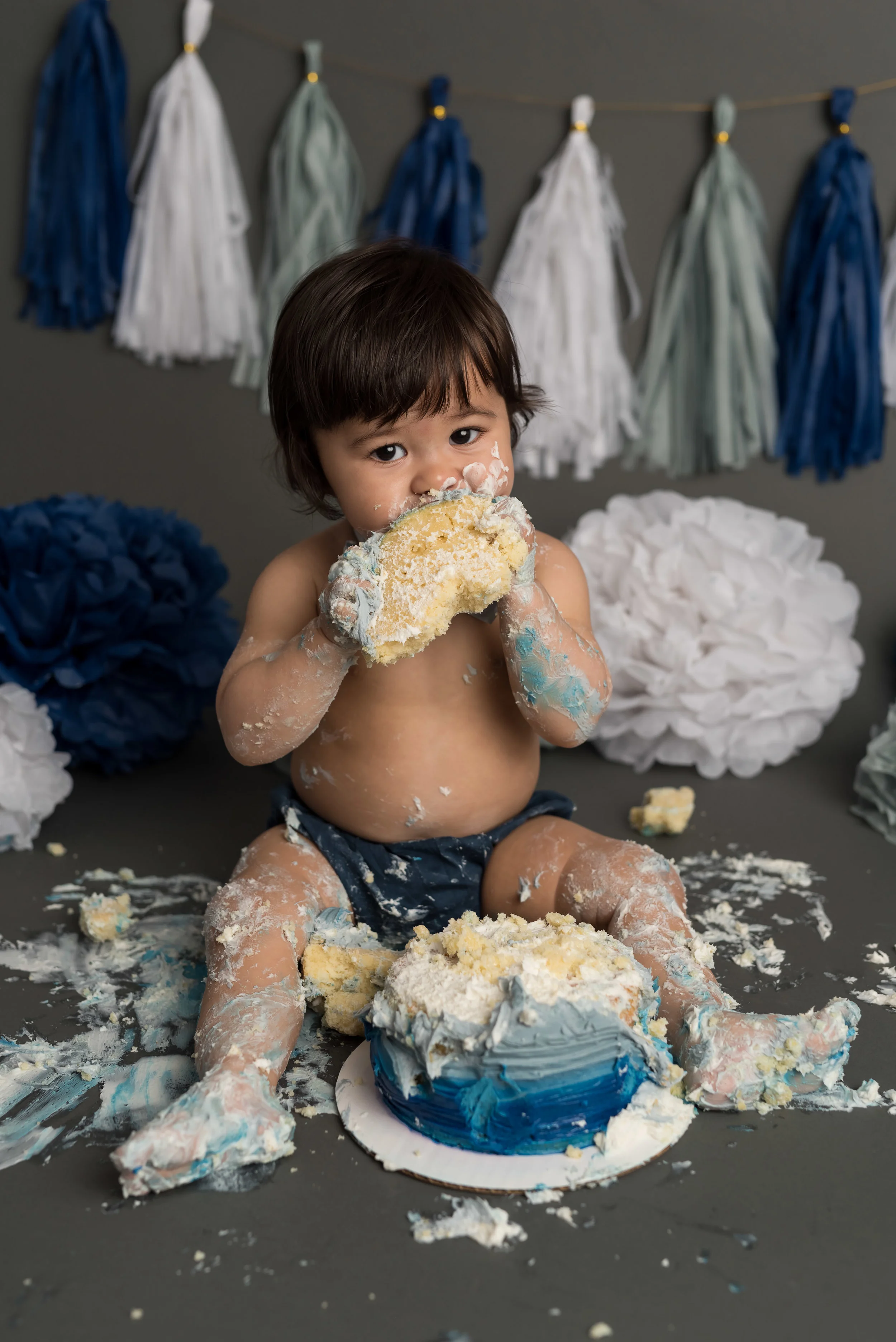little boy with a blue and grey theme, eating cake like a boss with junebug photography studio in manhattan, ks