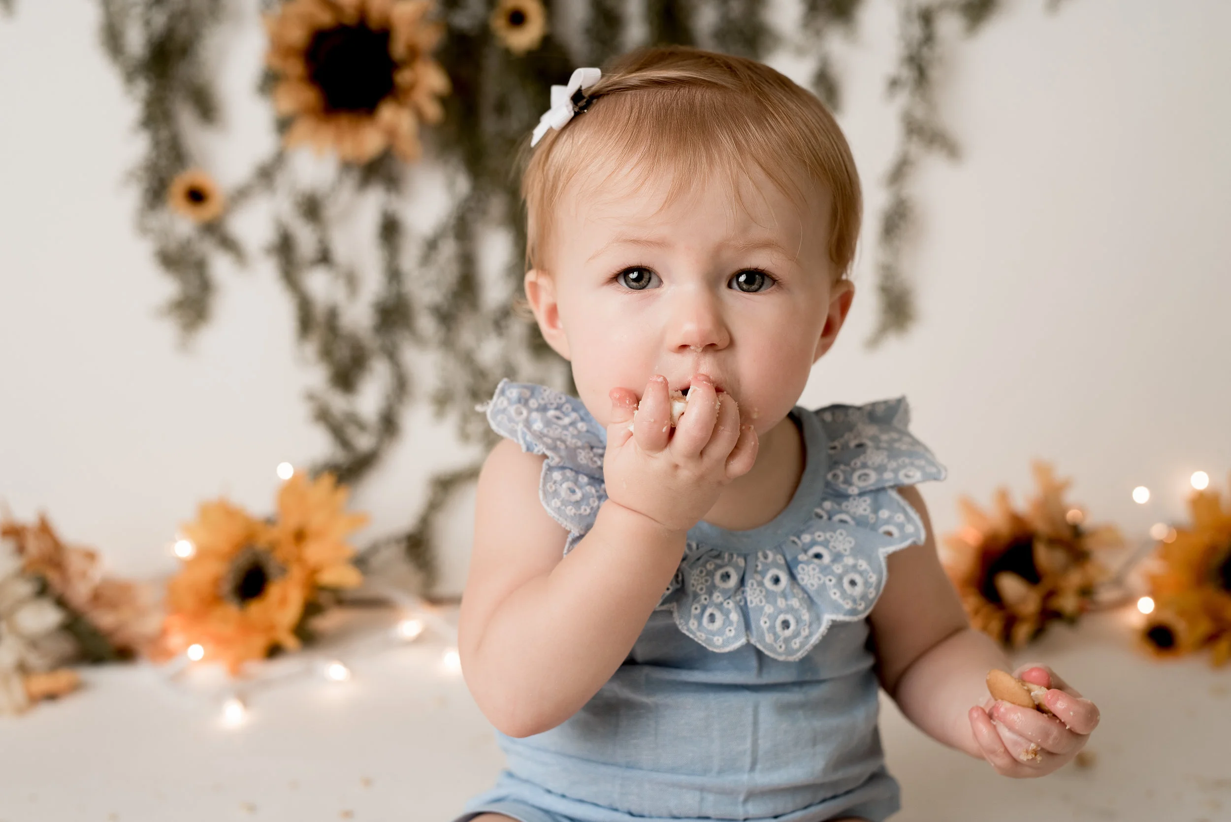 sunflower theme little girl eating her cake by the handful with junebug photography studio in manhattan, ks