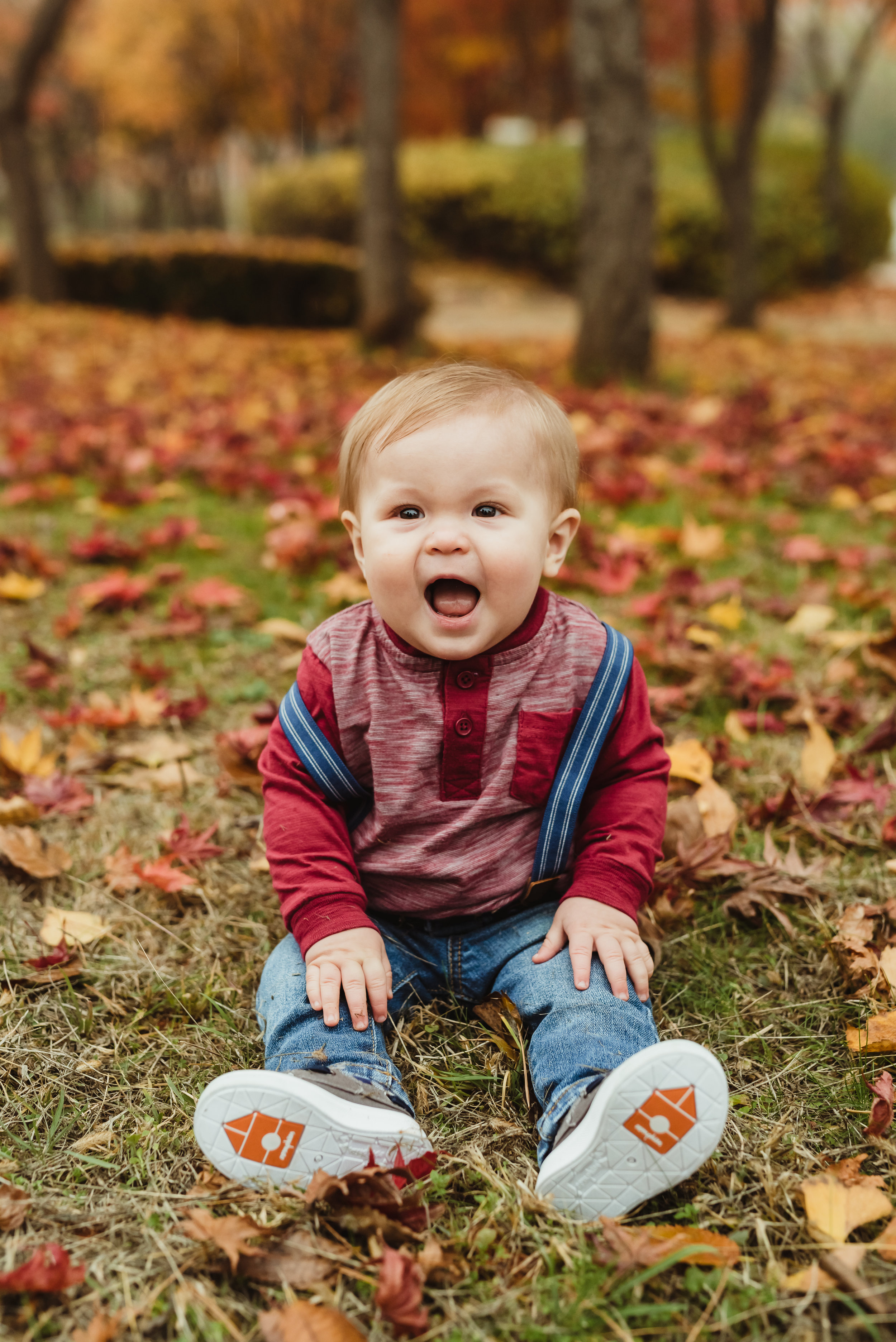 happy baby boy in some fall leaves with junebug photography studio in manhattan, ks