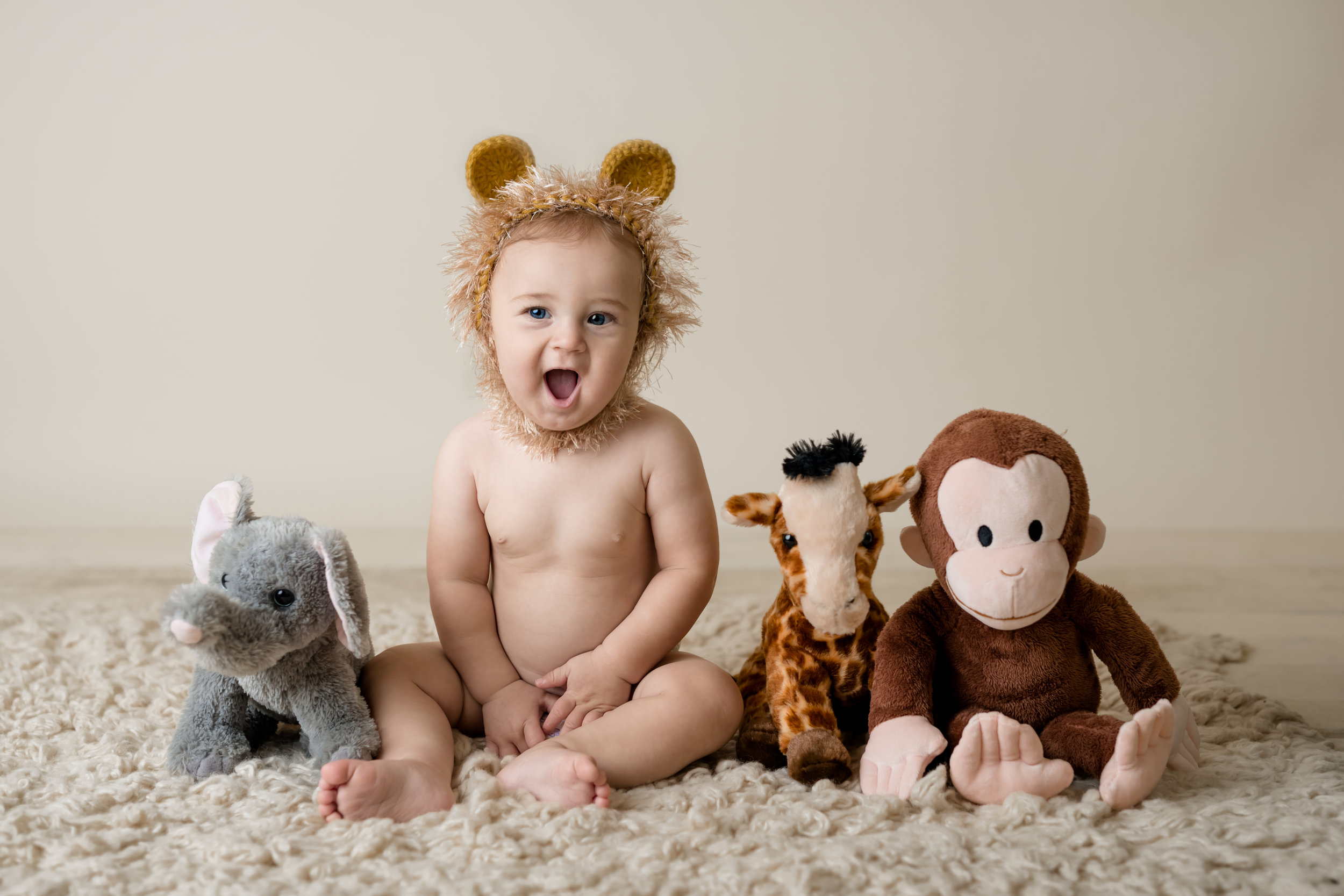 happy boy in a lion hat with the rest of his jungle animal friends with junebug photography studio in manhattan, ks